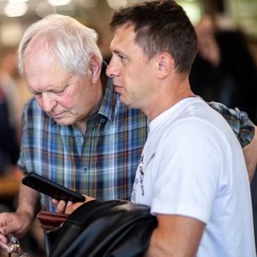 Das Bild zeigt Hans-Jürgen Lammers, wie auf das Smartphone eines Job-Suchenden schaut.