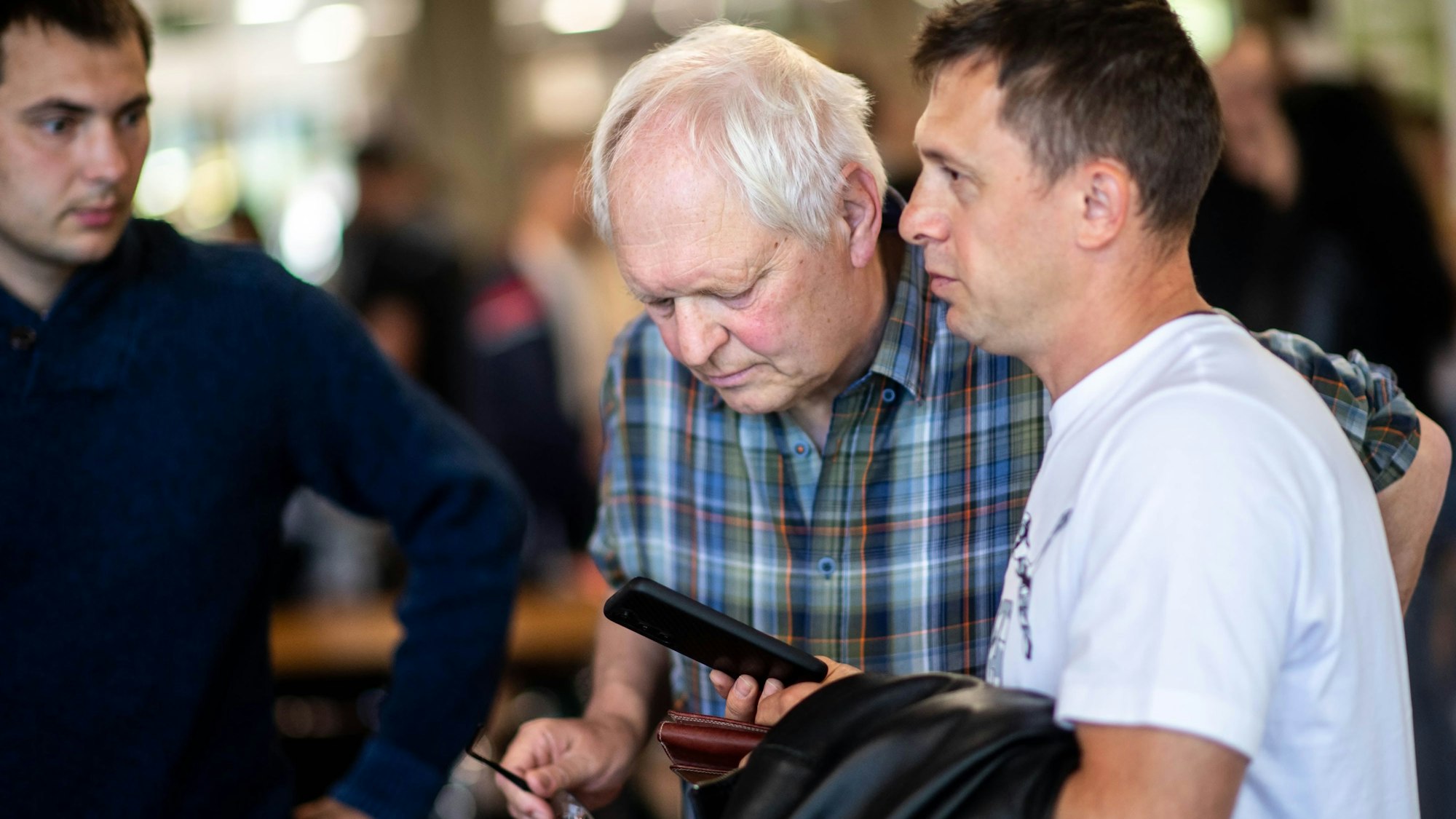 Das Bild zeigt Hans-Jürgen Lammers, wie auf das Smartphone eines Job-Suchenden schaut.