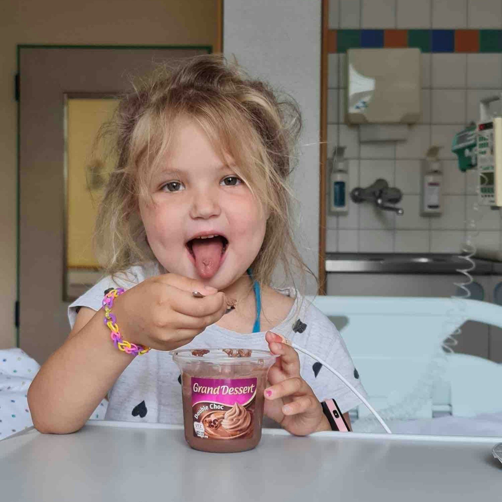 Das Foto zeigt Emily in ihrem Krankenzimmer. Sie isst einen Schokopudding.