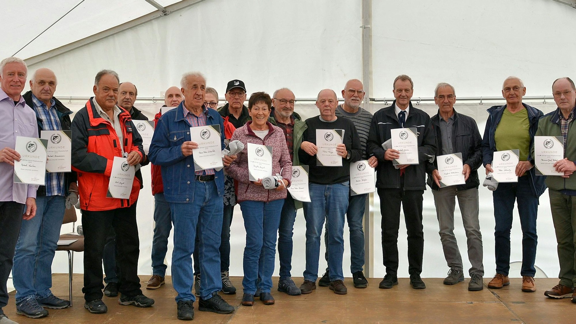 16 Männer und Frauenhaben sich zum Gruppenbild aufgestellt.