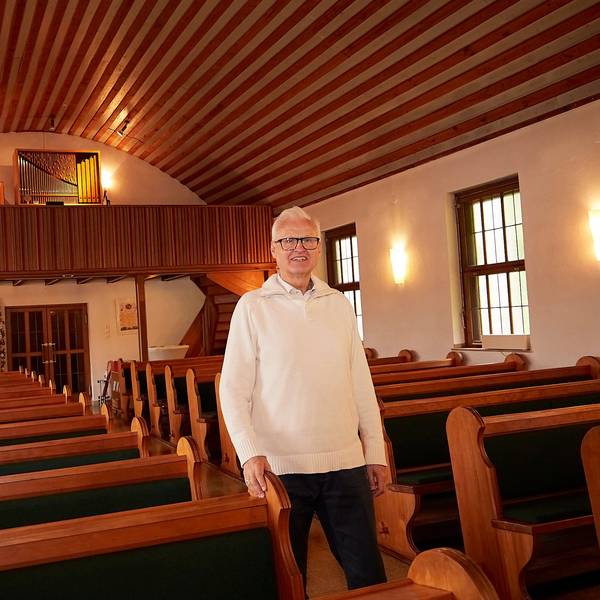 Pfarrer Christoph Cäsar geht durch den Mittelgang der evangelischen Kirche in Blankenheim. Rechts und links sind Bankreihen zu sehen, im Hintergrund die Orgel.