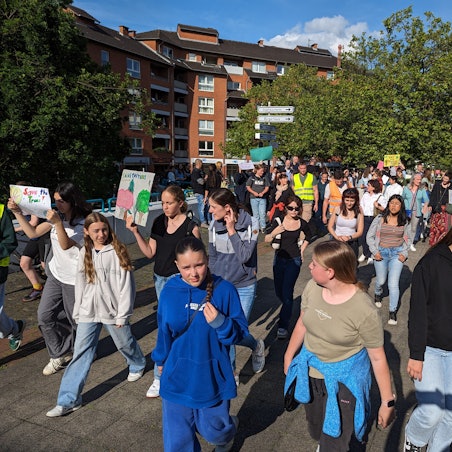 Ein Protestzug von Schülerinnen und Schülern mit Plakaten auf dem Plat vor dem Bürgerhaus.