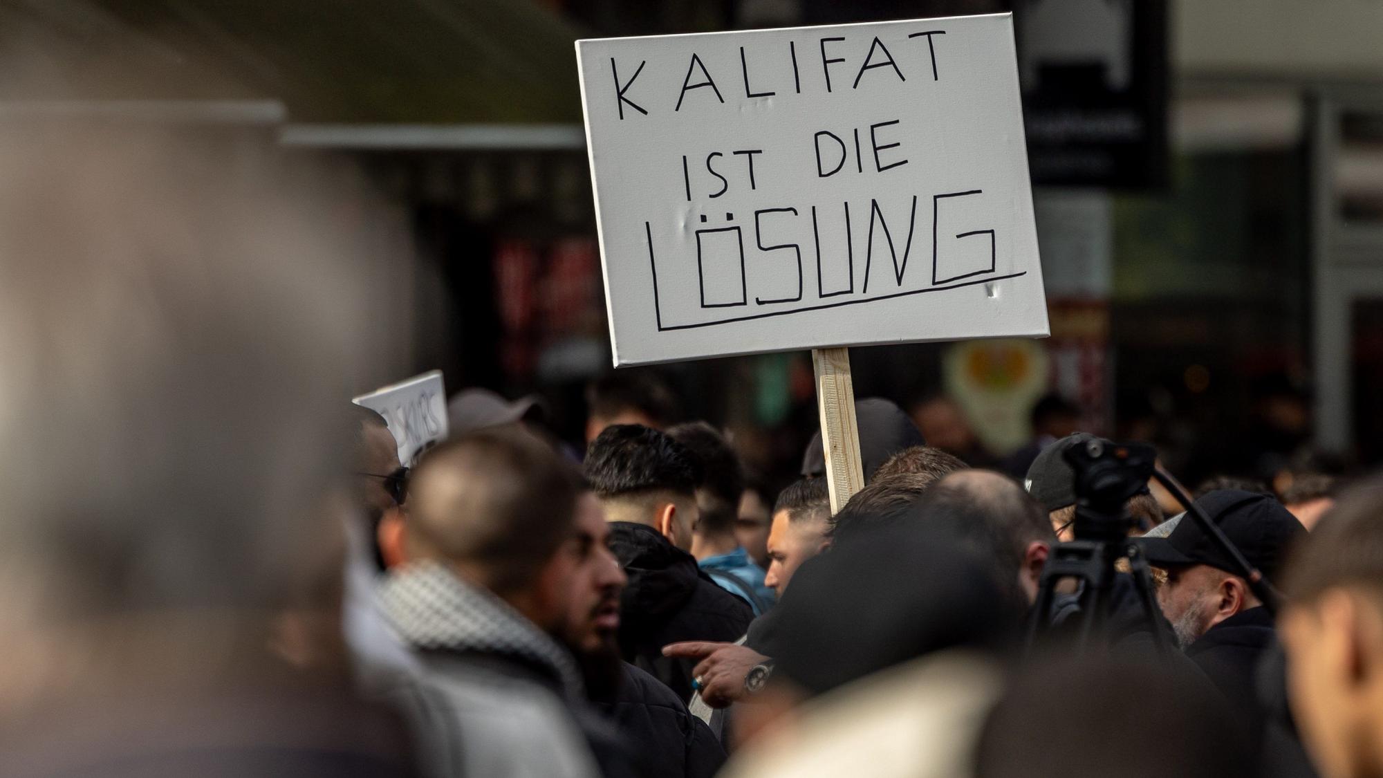 ARCHIV - 27.04.2024, Hamburg: Teilnehmer einer Islamisten-Demo halten ein Plakat mit der Aufschrift ·Kalifat ist die Lösung· in die Höhe. (zu dpa: «Buschmann zu Lob des Kalifats: Absurde Meinung ist nicht strafbar») Foto: Axel Heimken/dpa +++ dpa-Bildfunk +++