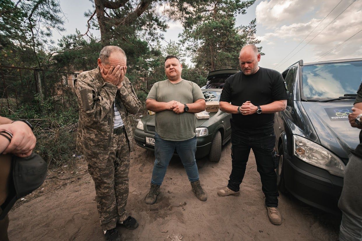 Mehrere Männer, einer in Militärkleidung, stehen in der Ukraine zusammen.