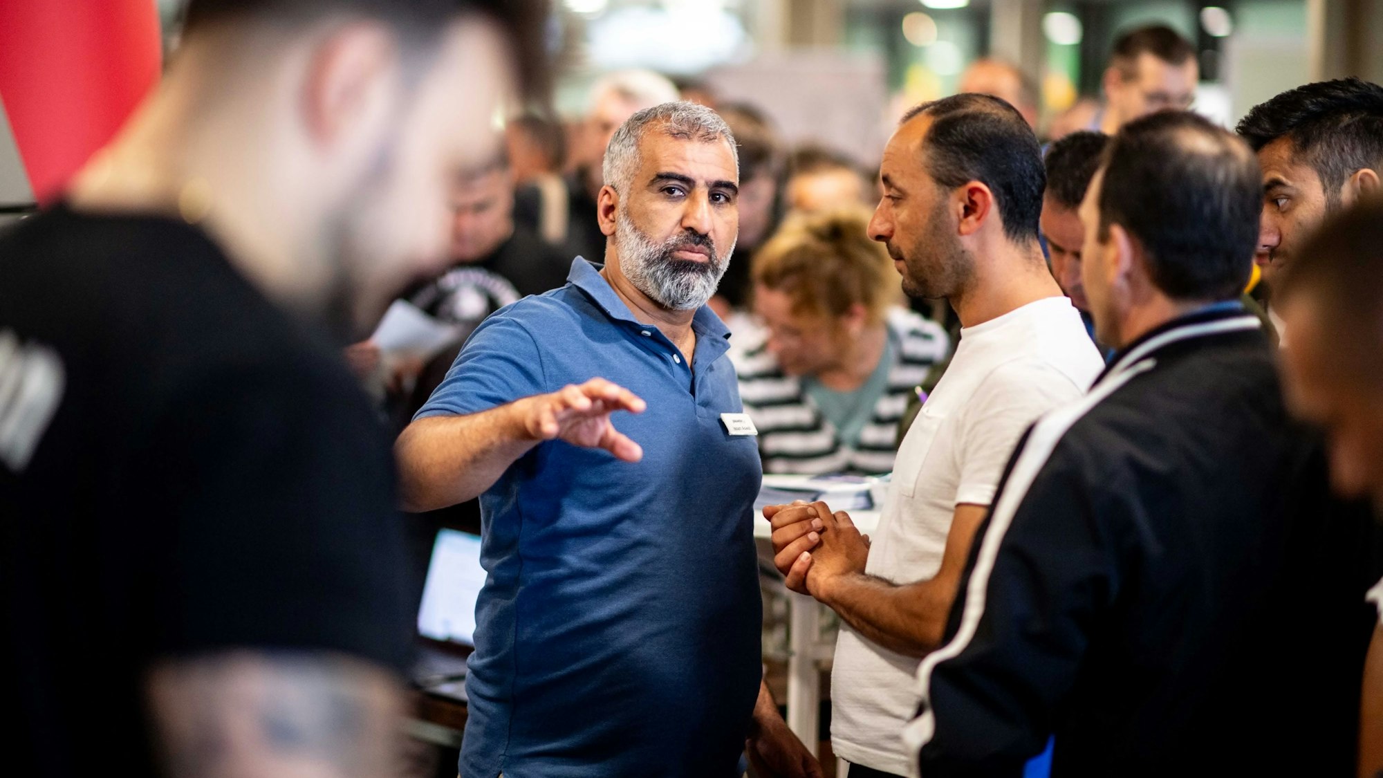Das Bild zeigt Issam Aswab im Gespräch mit einigen männlichen Job-Interessierten.