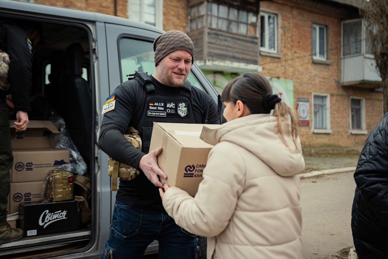 Ein Mann überreicht einer Frau ein Paket mit Hilfsgütern.