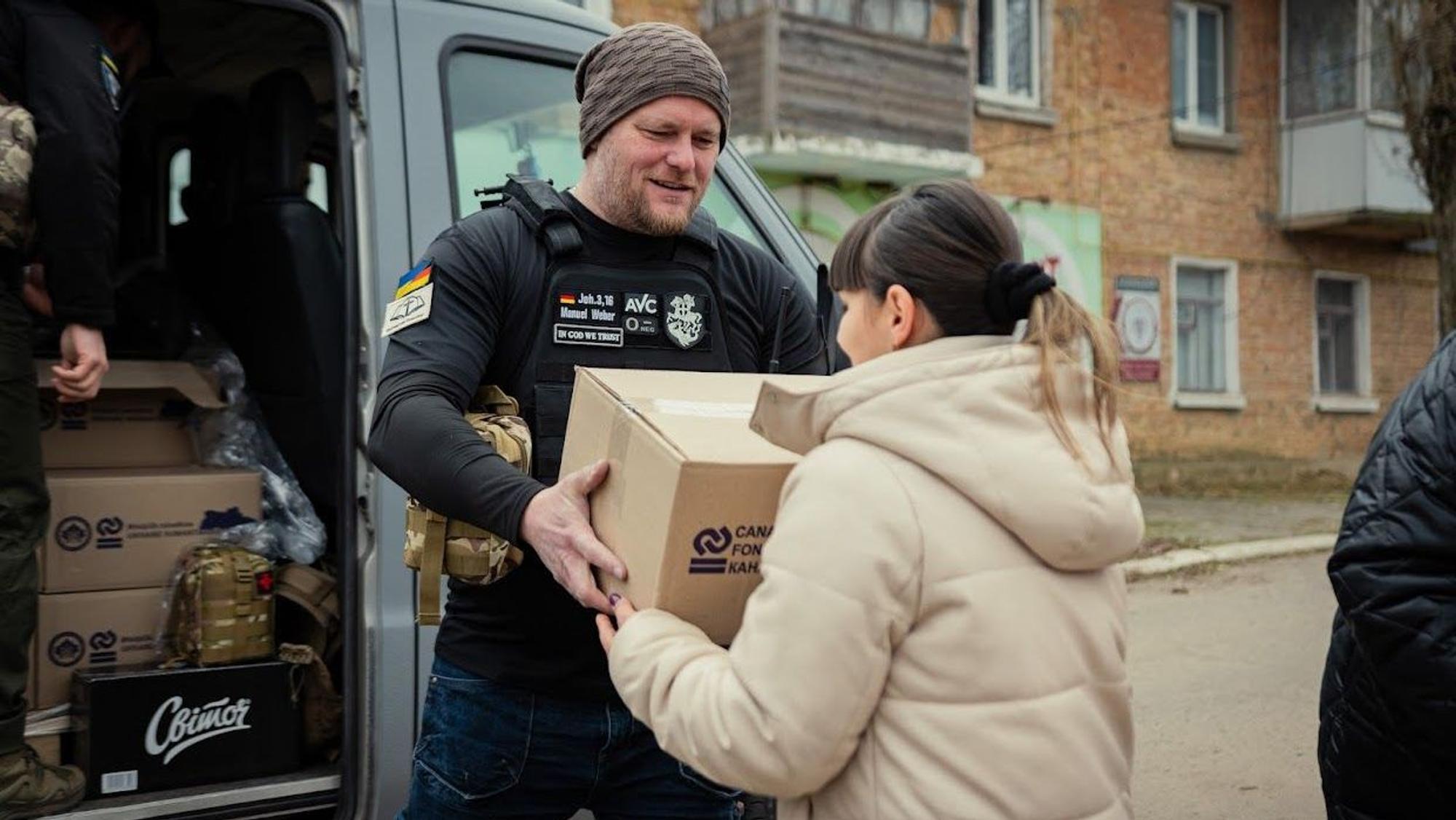 Ein Mann überreicht einer Frau ein Paket mit Hilfsgütern.