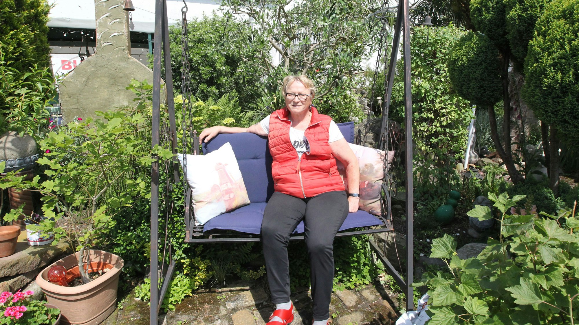 Offenen Gartenpforte In Niederkassel Lülsdorf hat Anita Eschbach einen grünen Daumen und sitzt auf der Bank in ihrem Idyll mit Palmen.