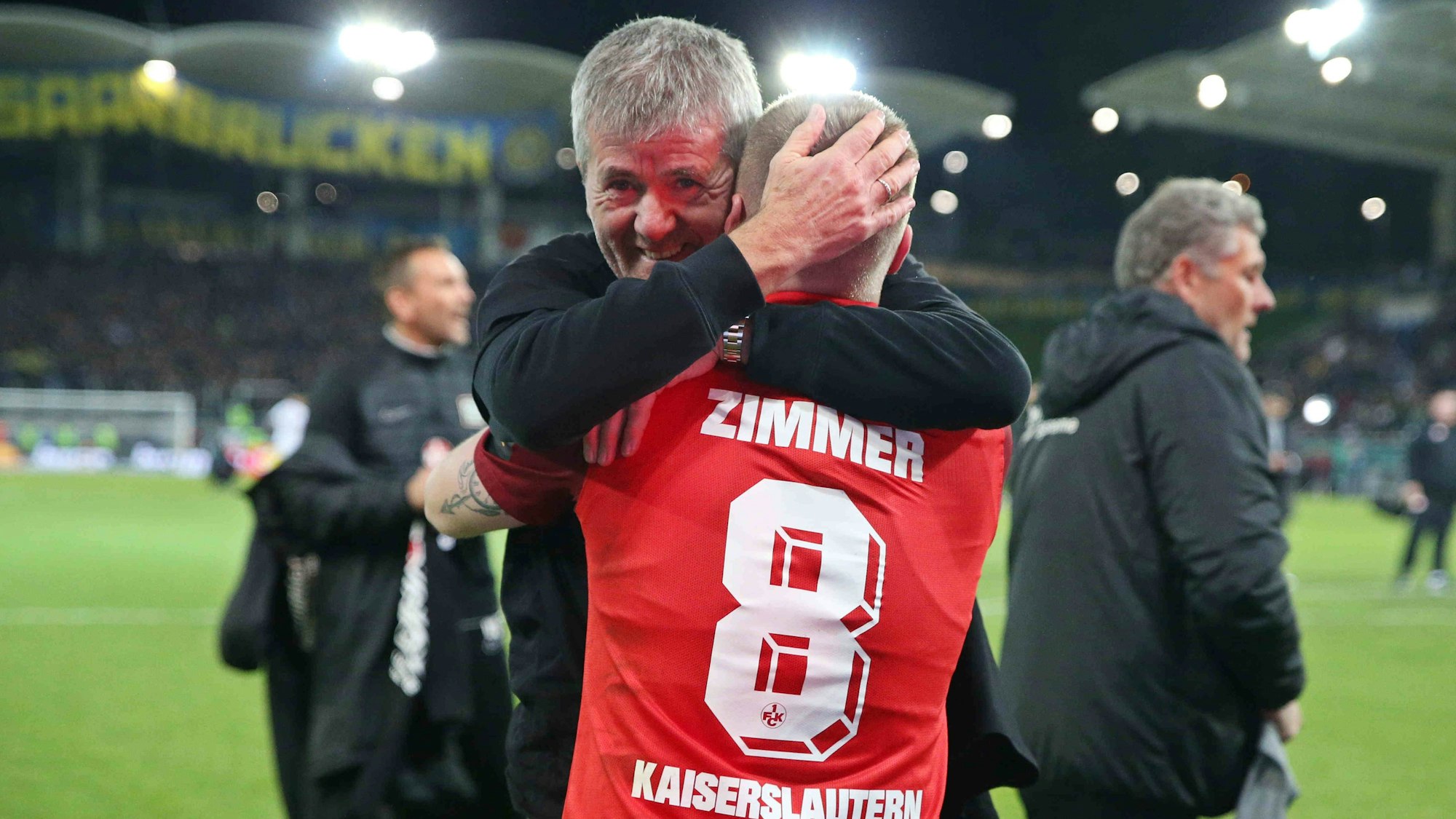 Die Spieler des 1. FC Kaiserslautern bejubeln gemeinsam mit den mitgereisten Fans den Einzug ins DFB-Pokal-Finale, Trainer Friedhelm Funkel umarmt Jean Zimmer.