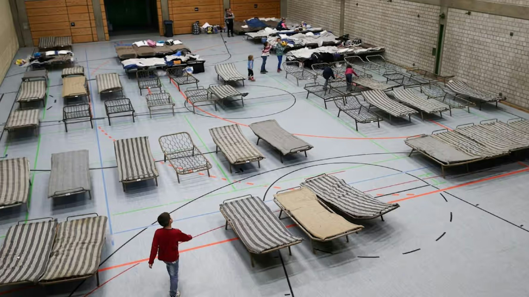 Auf dem Foto ist eine Turnhalle mit Feldbetten zu sehen.