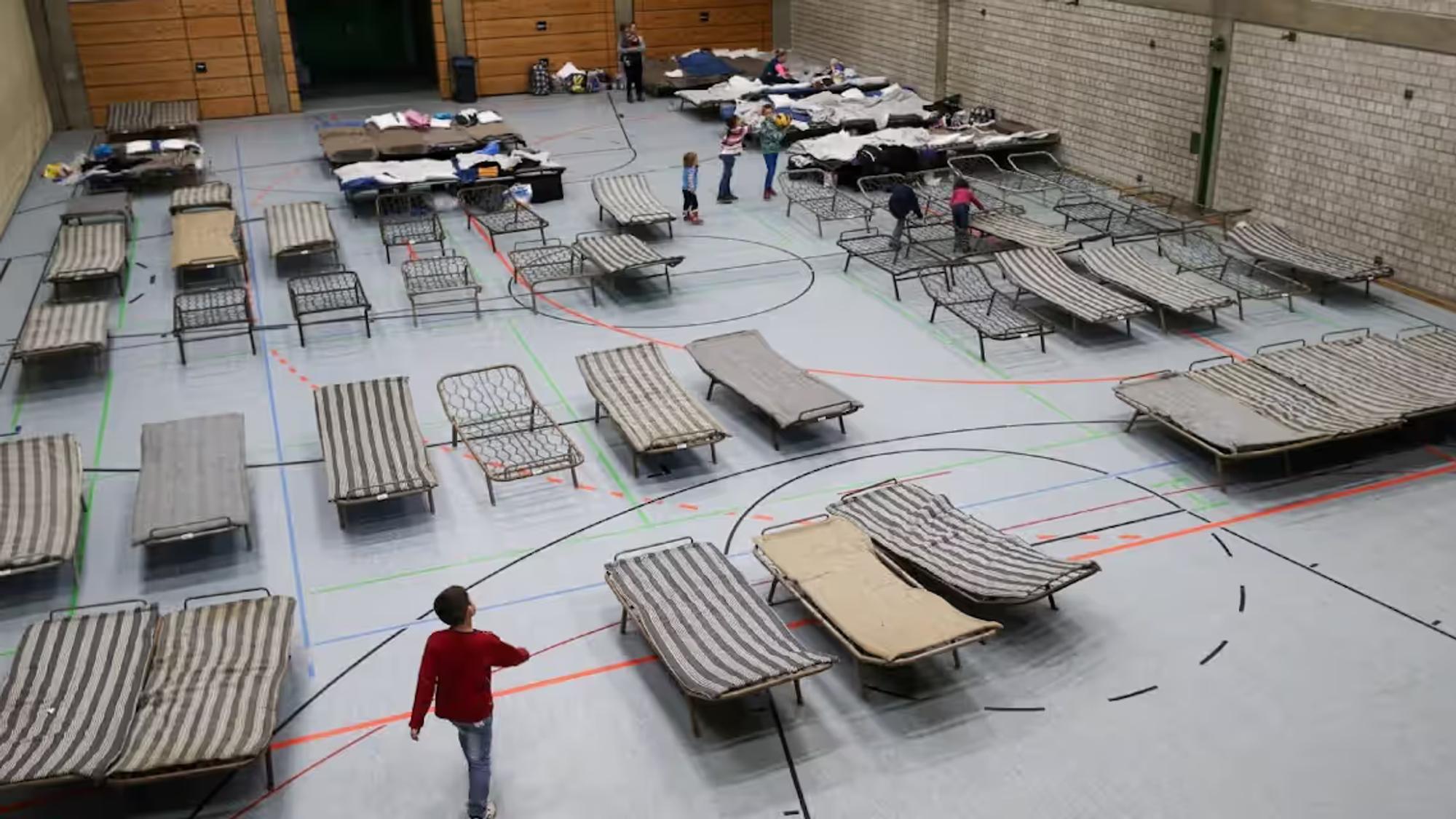 Auf dem Foto ist eine Turnhalle mit Feldbetten zu sehen.