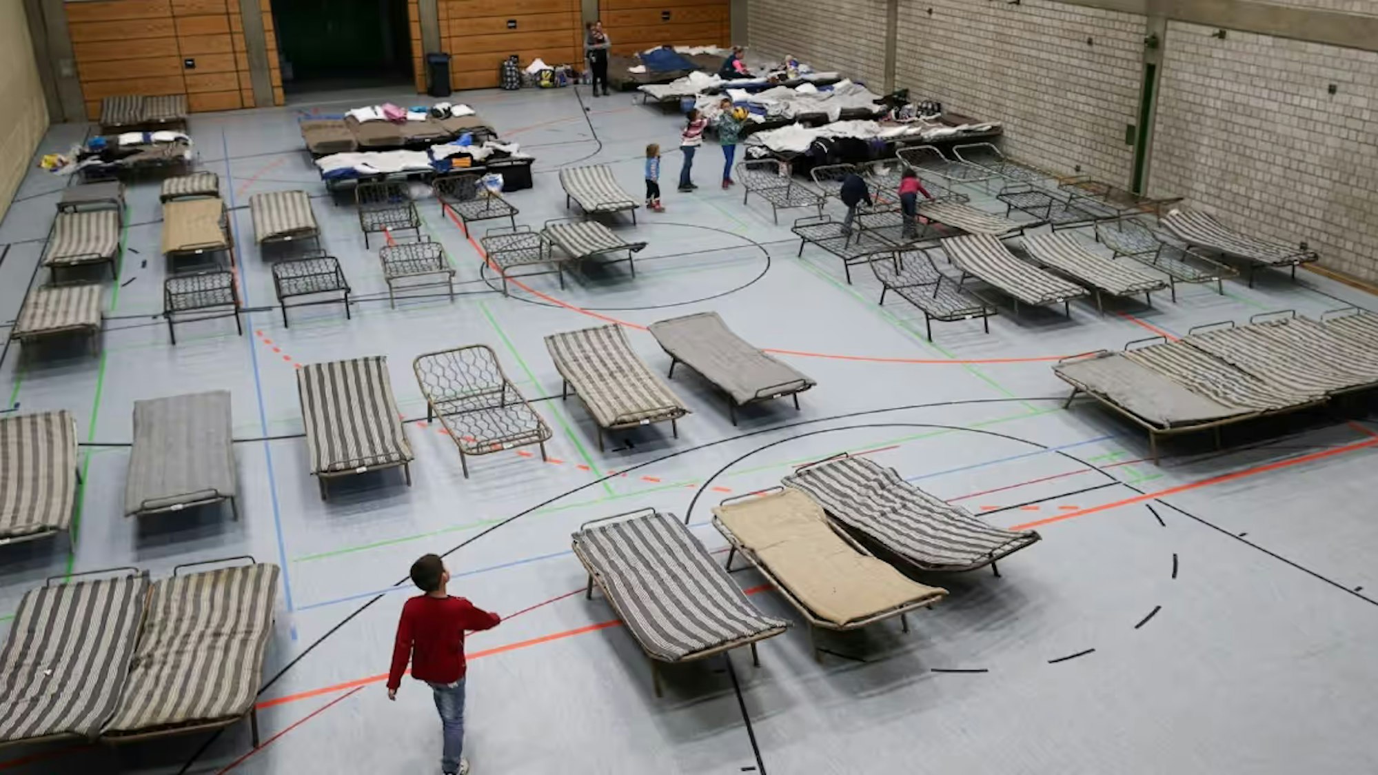 Auf dem Foto ist eine Turnhalle mit Feldbetten zu sehen.