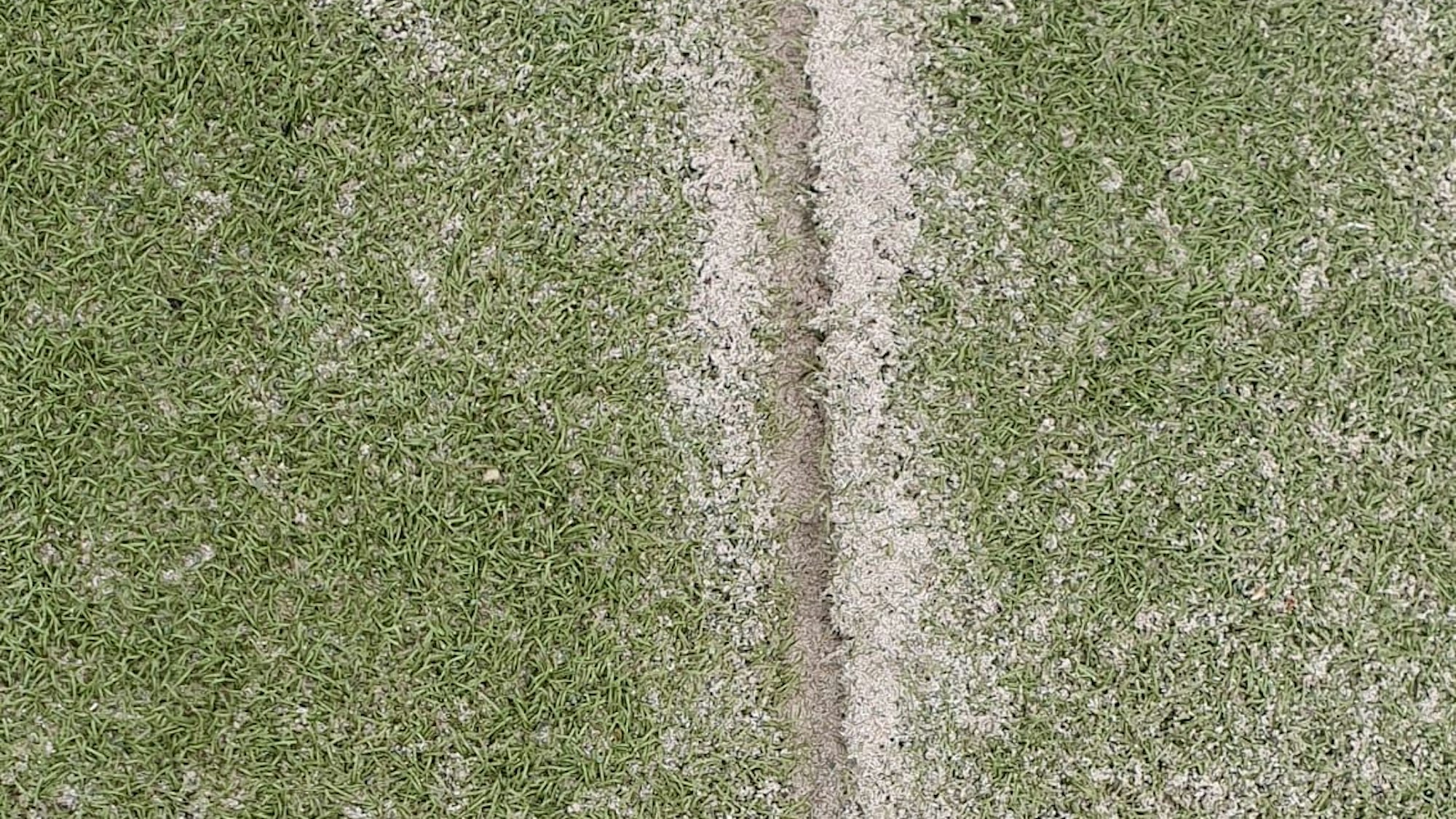 Auf dem Bild ist ein kaputter Kunstrasen zu sehen.