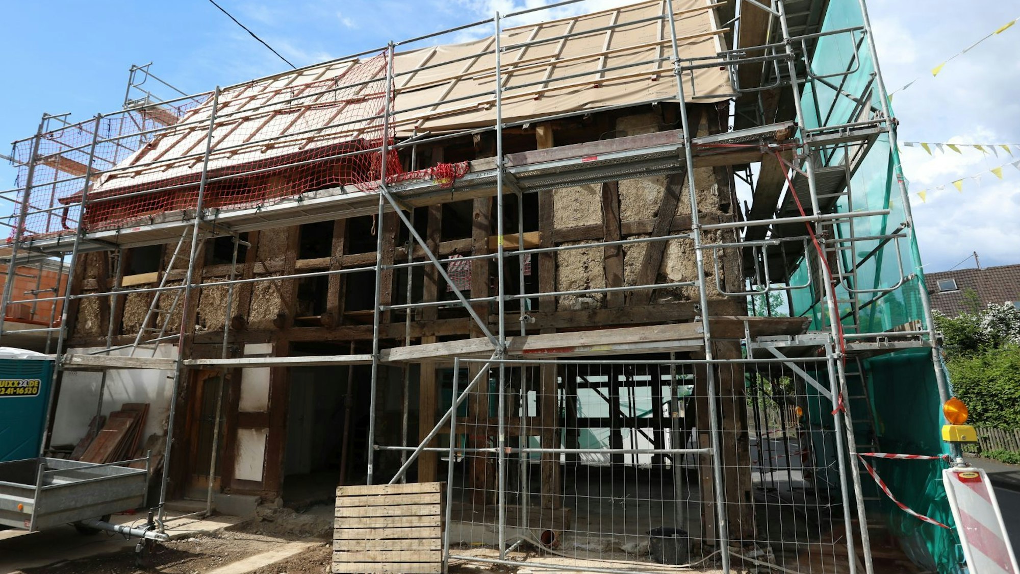 Ein Fachwerkhaus, an dem die meisten Balken freistehen und die Gefache fehlen, ist eingerüstet.