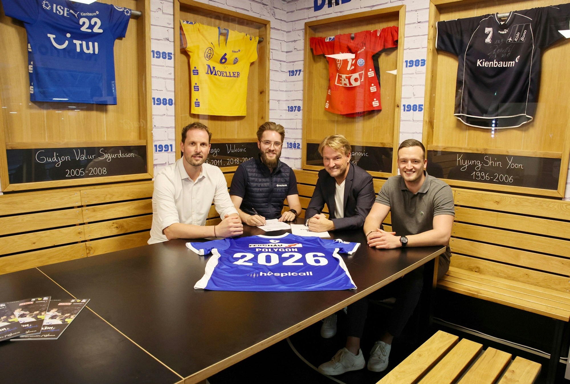 Bei der Vertragsunterzeichnung: Christoph Schindler, Florian Lister, Markus Krampe und Dennis Römer sitzen nebeneinander. Vor ihnen liegt ein VfL-Trikot mit der Nummer 2026.