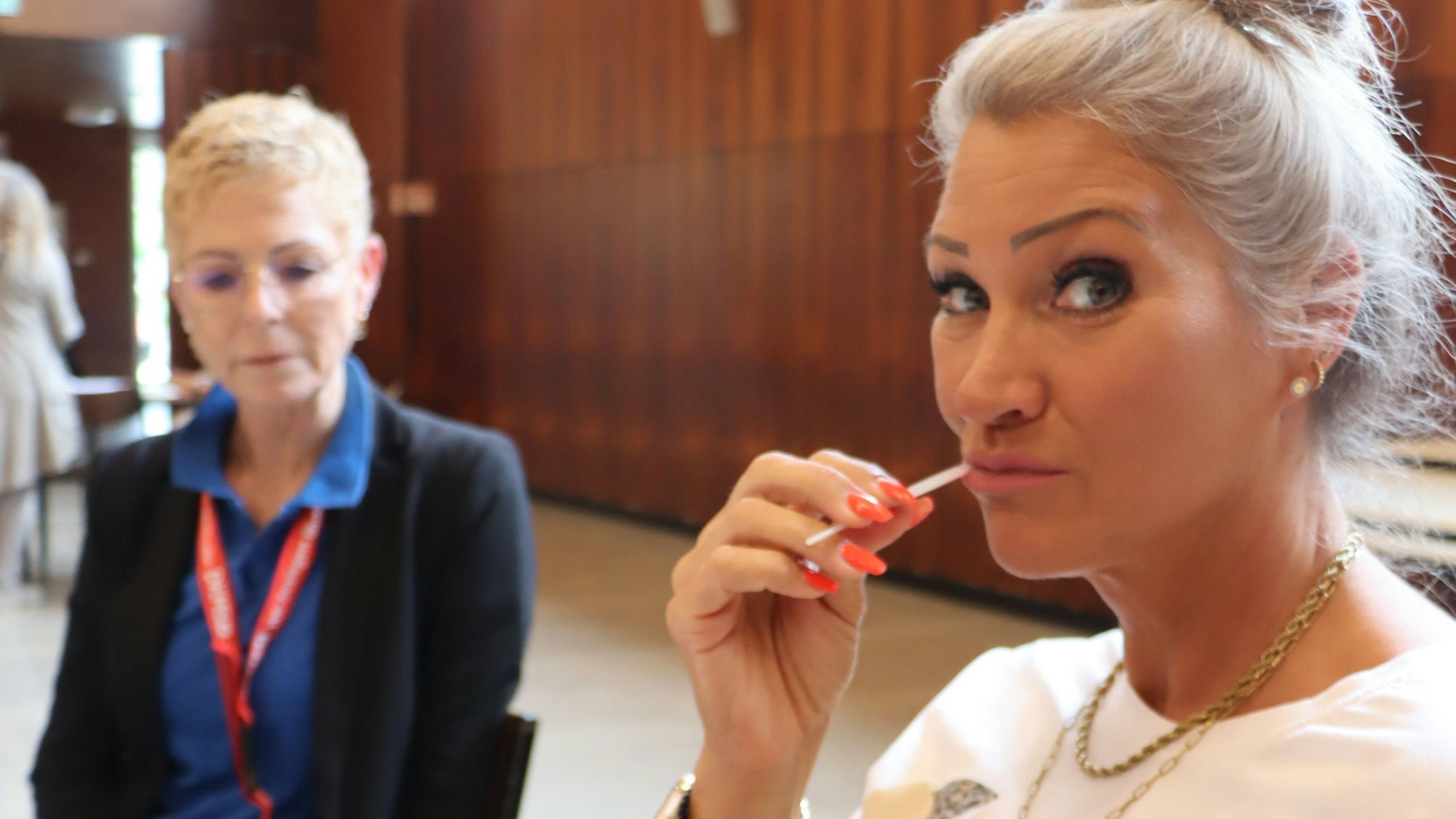 Zu sehen ist eine Frau, die sich mit einem Wattestäbchen eine Probe an der Mundschleimhaut entnimmt.