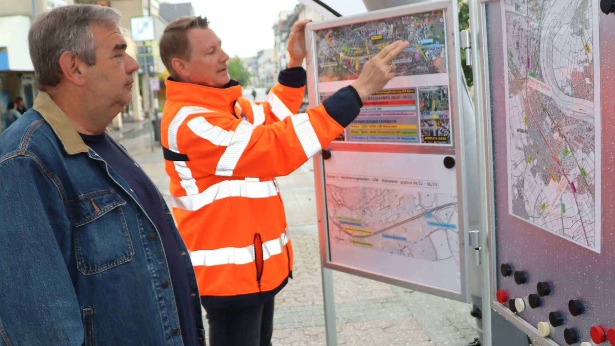 Zu sehen ist Helge Wego, der einem Bürger einen Bauplan erläutert.