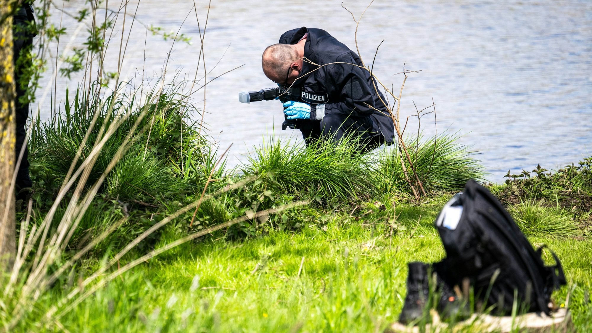 Ein Polizist fotografiert einen Hinweis am Ufer der Oste auf der Suche nach dem vermissten Arian. Die Ermittler vermuten, dass der autistische Junge in den Fluss gestürzt sein könnte.
