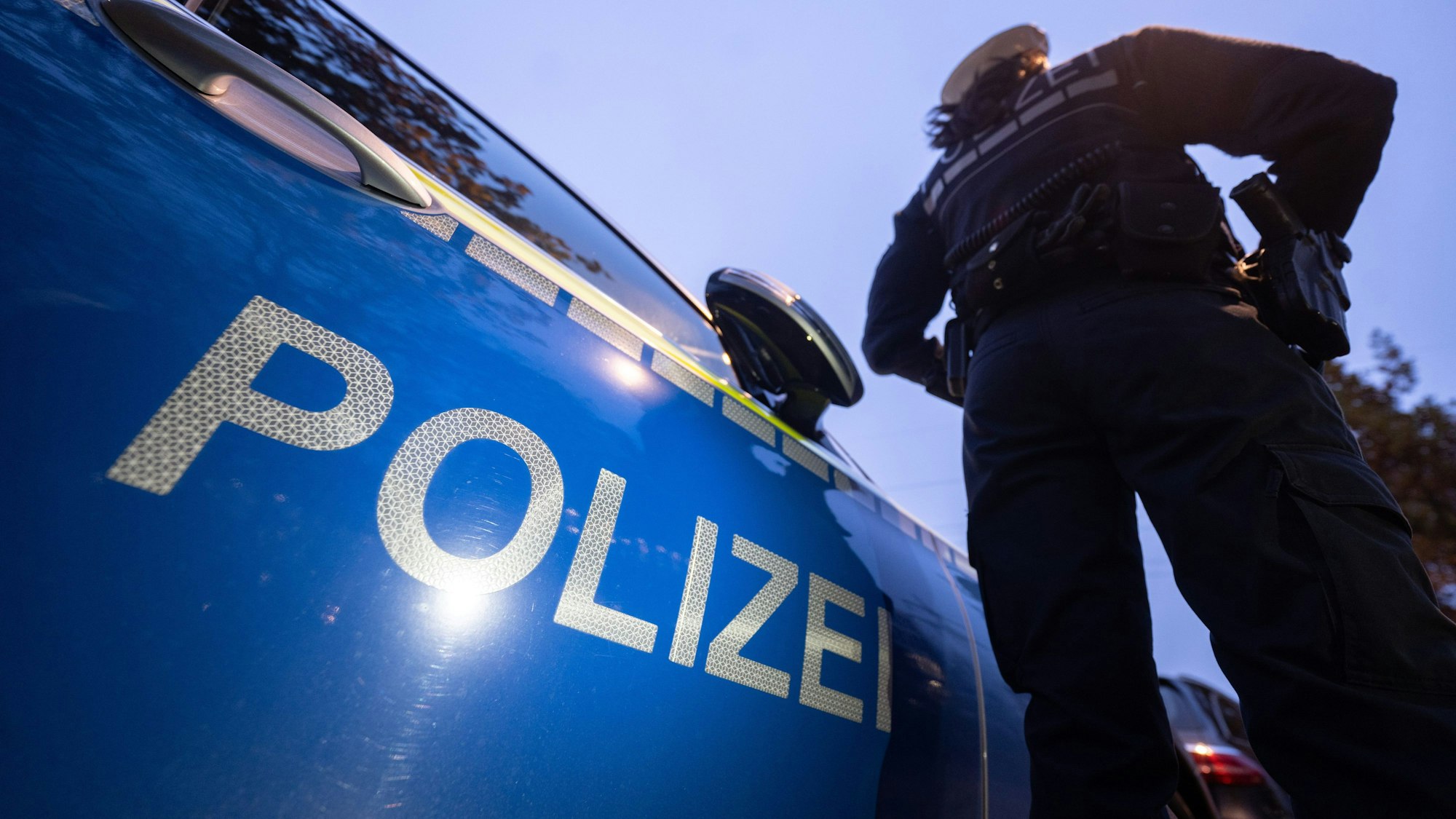 ILLUSTRATION - 30.11.2023, Baden-Württemberg, Stuttgart: Eine Polizistin steht neben einem Polizeifahrzeug. (zu dpa «Gegendemonstranten stoppen Demozug in Frankfurt - eine Festnahme») (zu dpa: «Zwei Festnahmen bei Demonstrationen in Frankfurt») Foto: Marijan Murat/dpa +++ dpa-Bildfunk +++