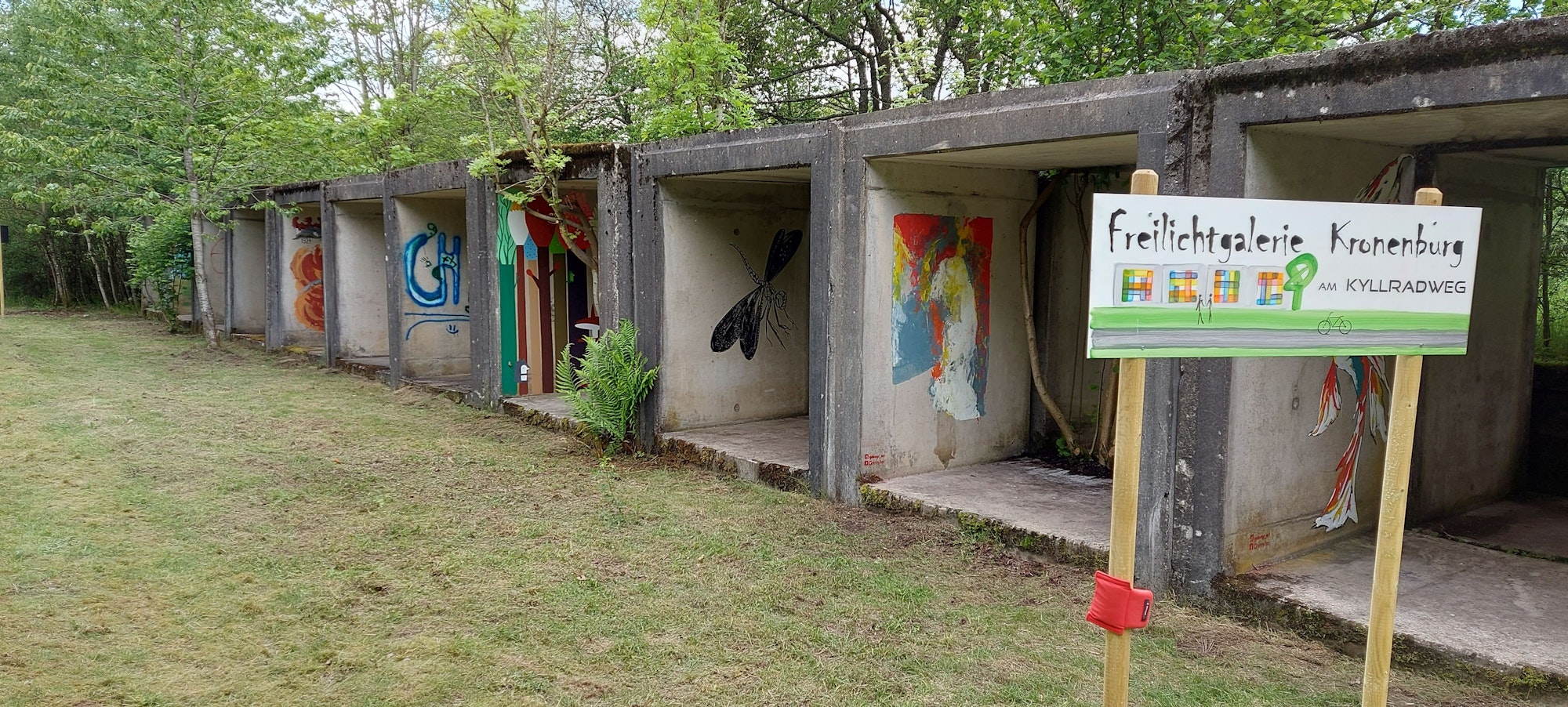 Die Galerie besteht aus Betonhohlformen, die, von Grün umgeben, mit Wandmalereien versehen worden sind.