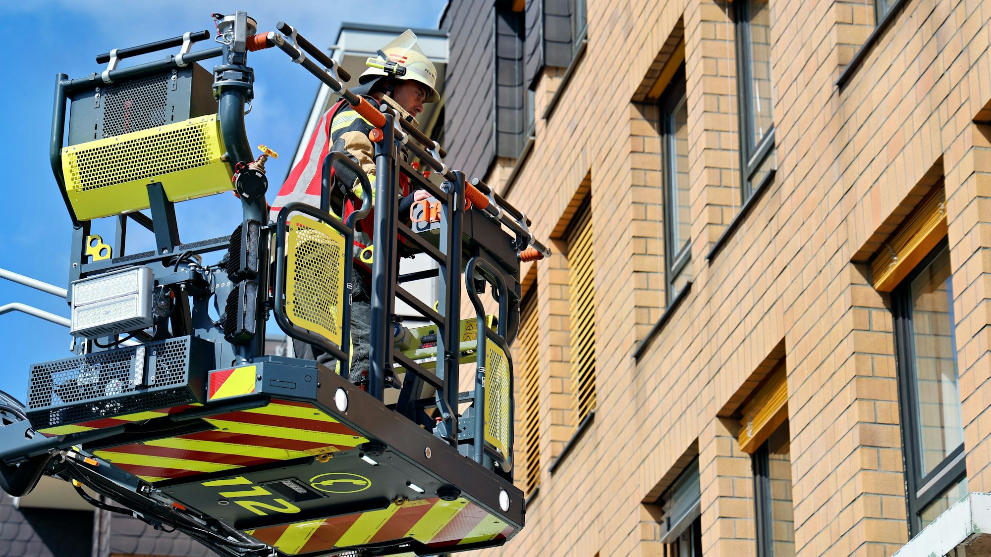 Im Drehleiterkorb lässt sich ein Feuerwehrmann an den Fenstern des Seniorenzentrums vorbeifahren.