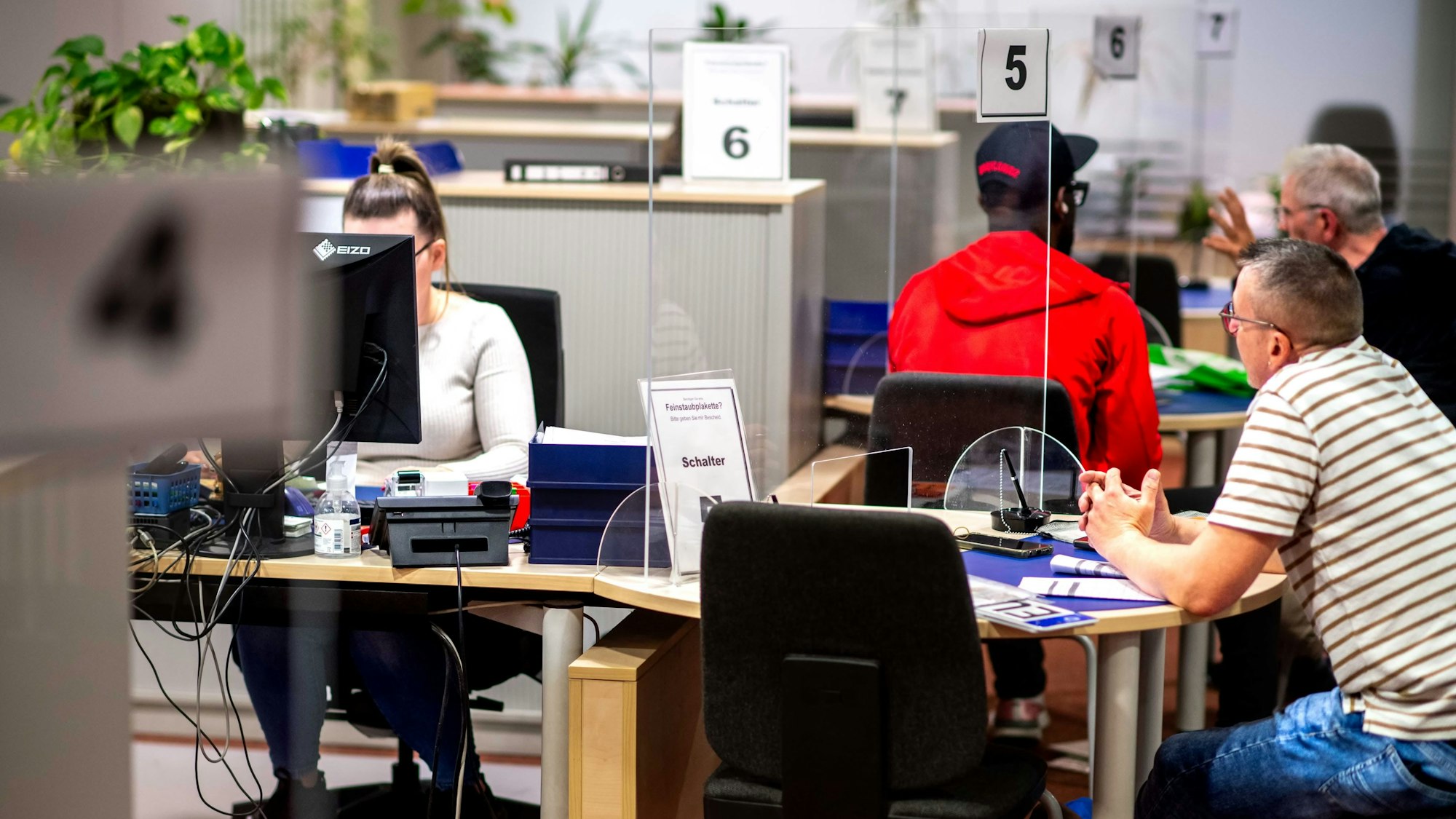 Ein Blick in die Zulassungsstelle mit Personal und Kunden.