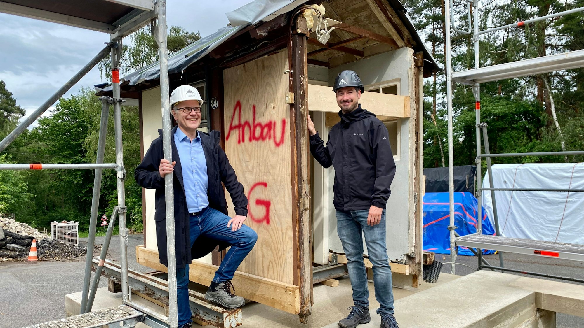 Raphael Thörmer und Dr. Carsten Vorwig posieren entspannt neben dem bereits montierten Toilettenhaus im LVR-Freilichtmuseum Kommern.