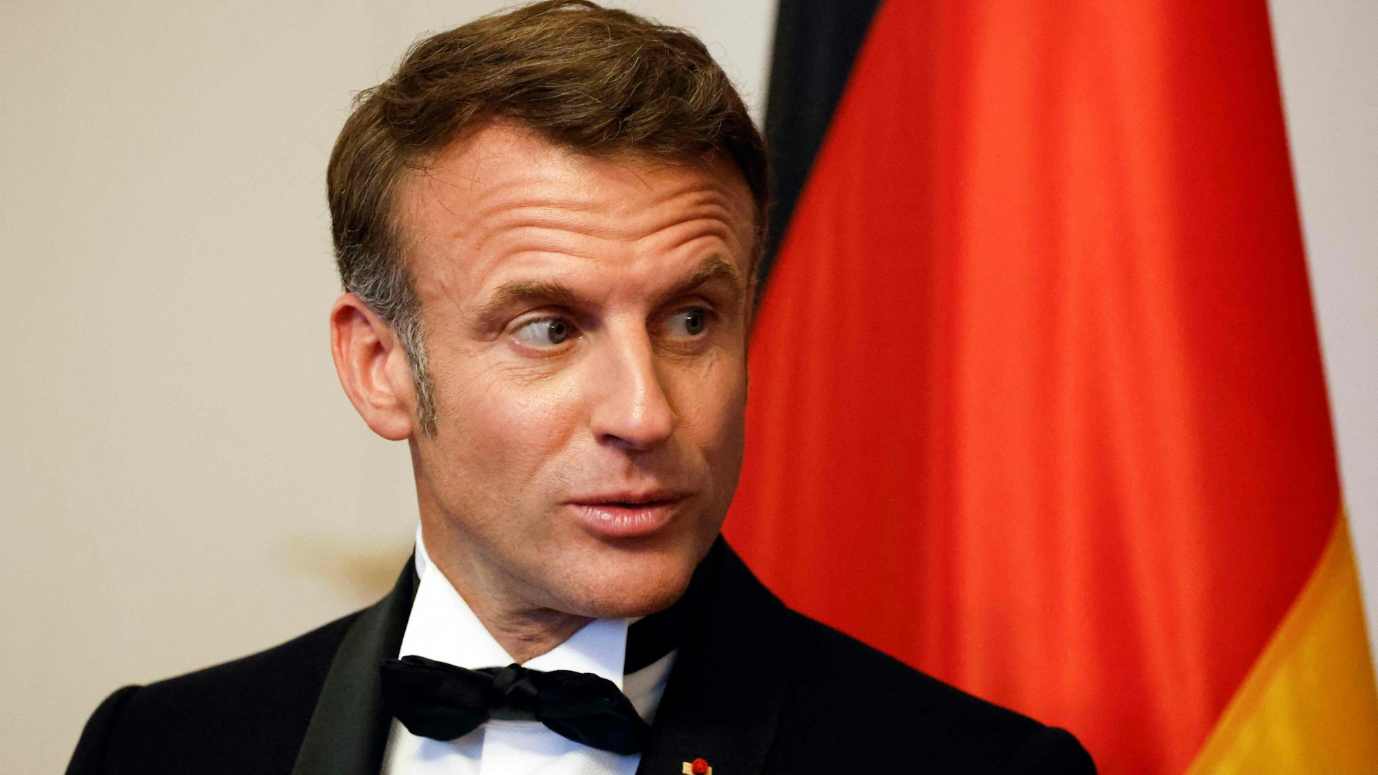 French President Emmanuel Macron stands in front of the German flag during a State Banquet at Bellevue presidential palace in Berlin on May 26, 2024, during his state visit. (Photo by Ludovic MARIN / AFP)