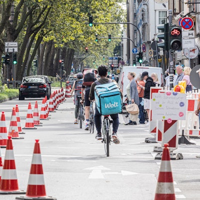 Eine Radspur ist auf der Luxemburger Straße mit Pylonen abgetrennt. Links fahren die Autos, rechts die Radfahrenden.