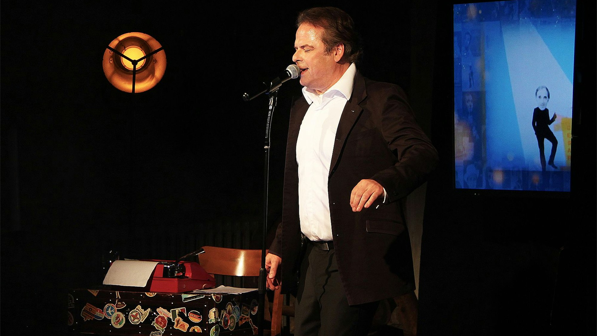 Auf einer abgedunkelten Bühne in Steinfeld steht der Sänger und Schauspieler Stephan Hippe.