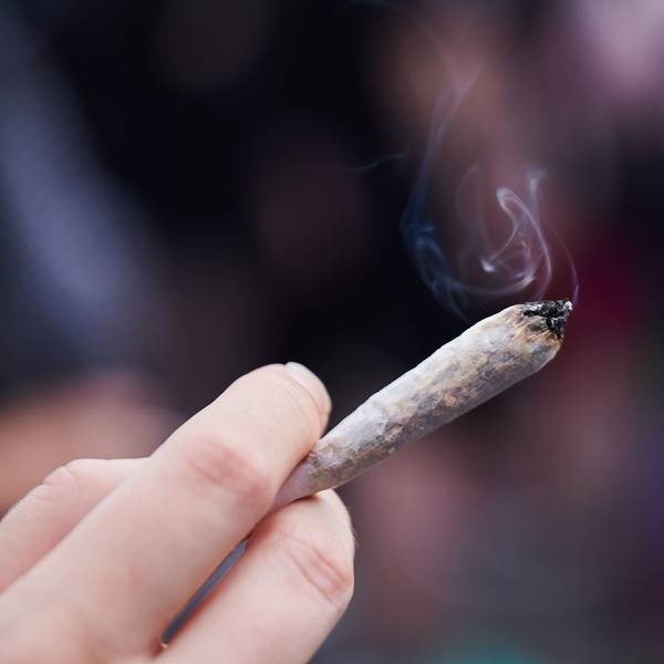 Eine Frau hält einen Joint in der Hand.