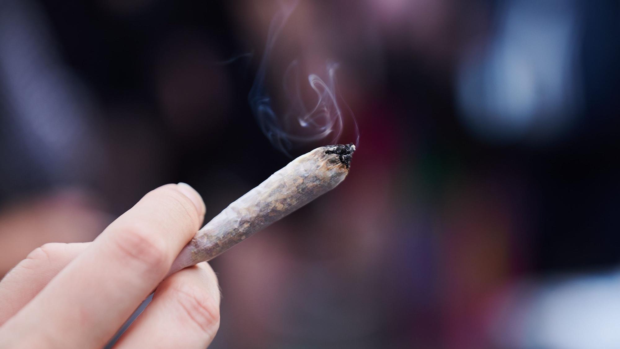 Eine Frau hält einen Joint in der Hand.
