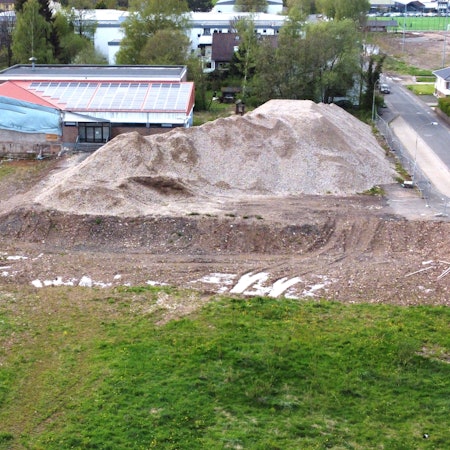 Blick auf die alte Turnhalle, neben der ein großer Schutthaufen liegt.