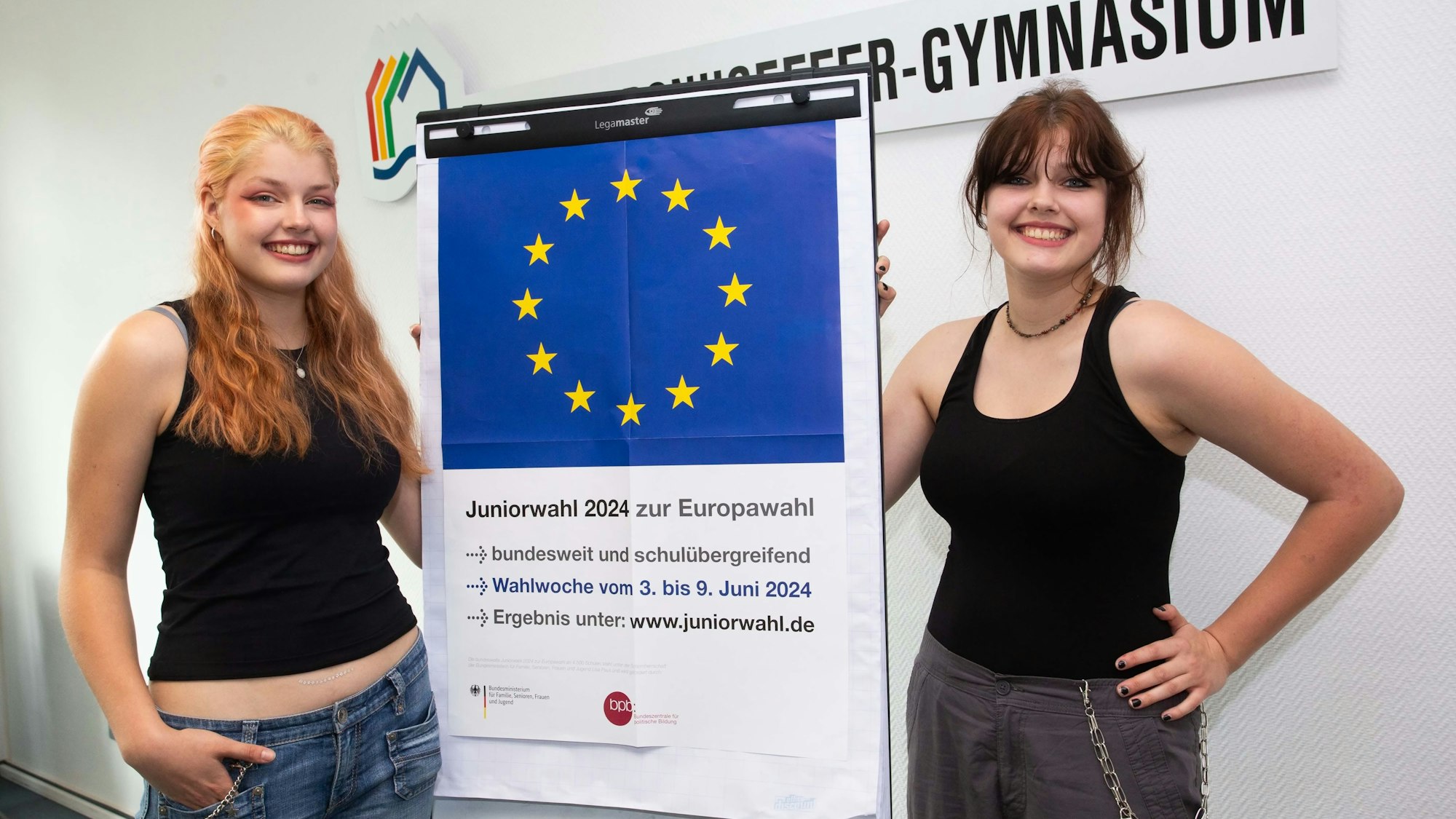 Zwei Schülerinnen vor einem Plakat.
