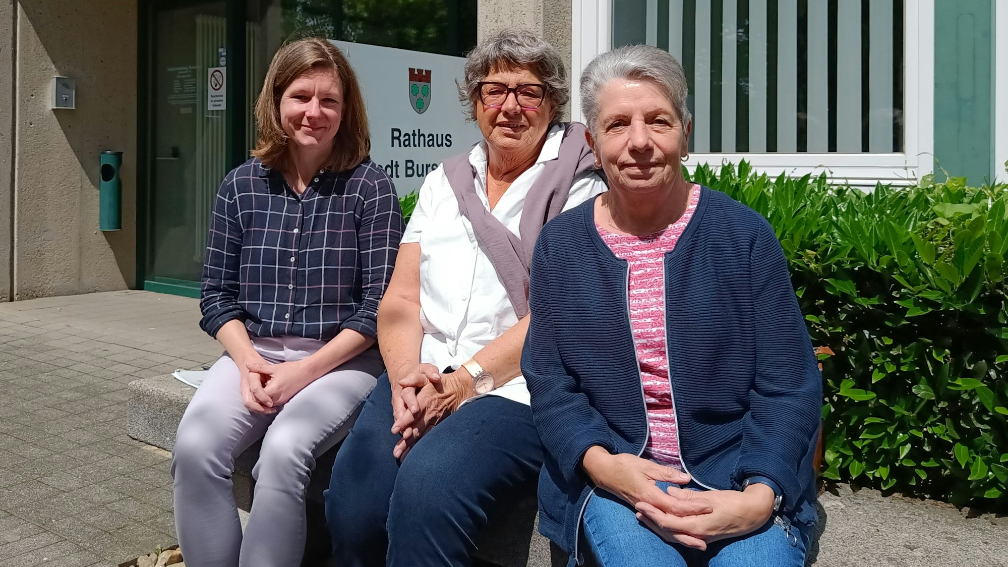 Helga Coen und Margret Eimermacher aus dem Seniorenbeirat sitzen mit Schriftführerin Jenny Zyball vor dem Burscheider Rathaus.