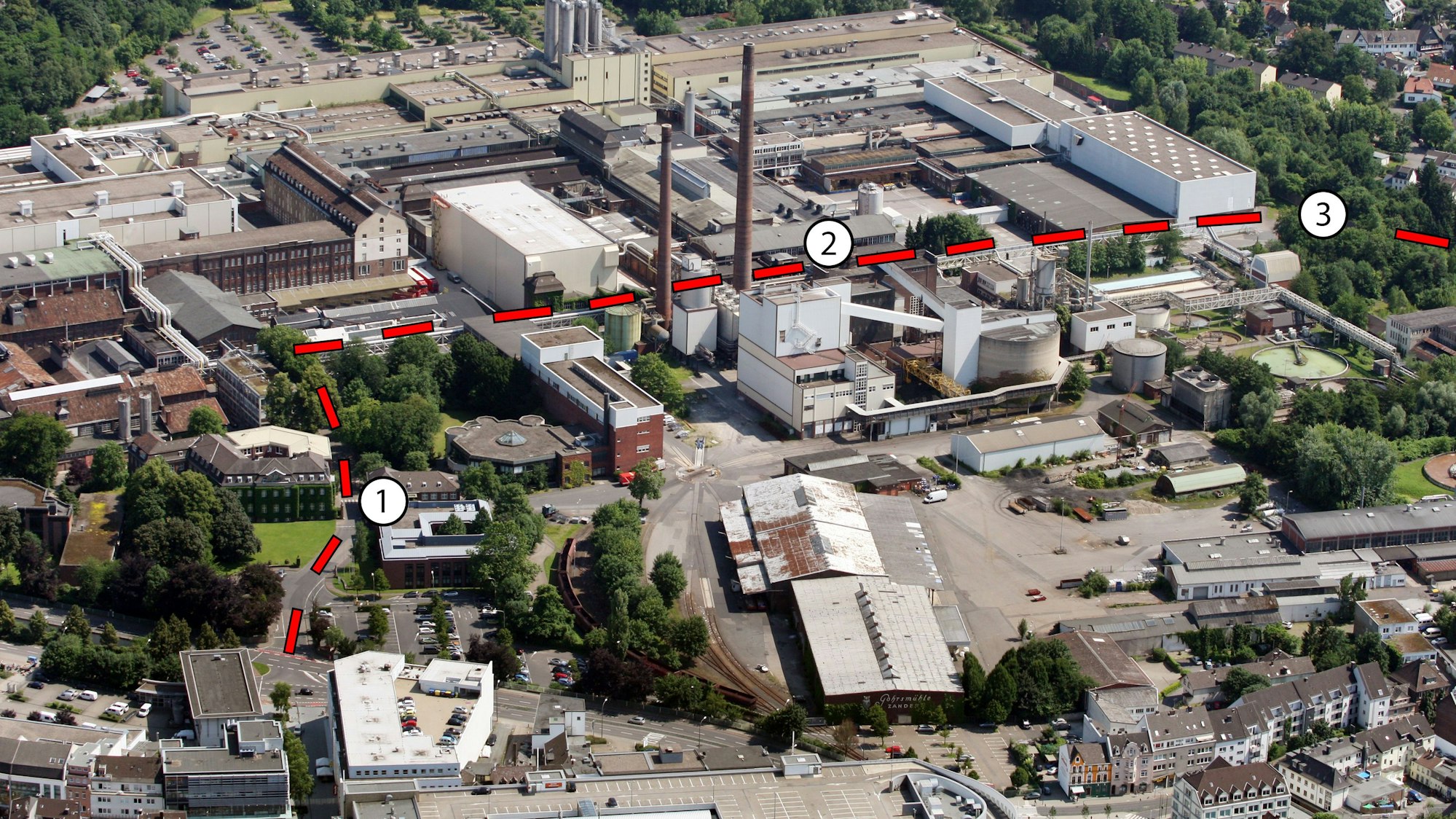 das Zanders-Areal aus der Vogelperspektive von einem Flugzeug aus gesehen. Eingezeichnet ist die am 25. Mai 2024 freigegebene Straße über das Gelände.