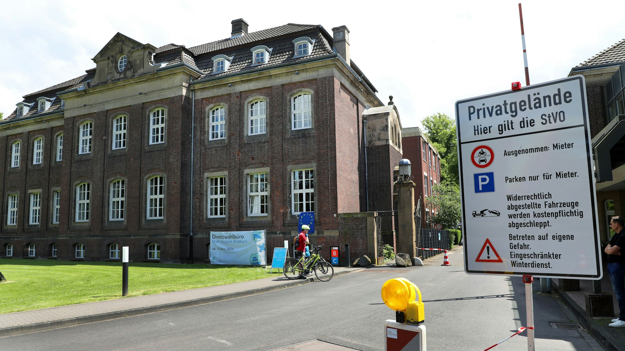 Neben einem Tor und dem historischen Hauptgebäude des Zanders-Geländes steht ein Schild, das unter anderem angibt, dass es sich um ein Privatgelände handelt, auf dem die Straßenverkehrsordnung gilt.