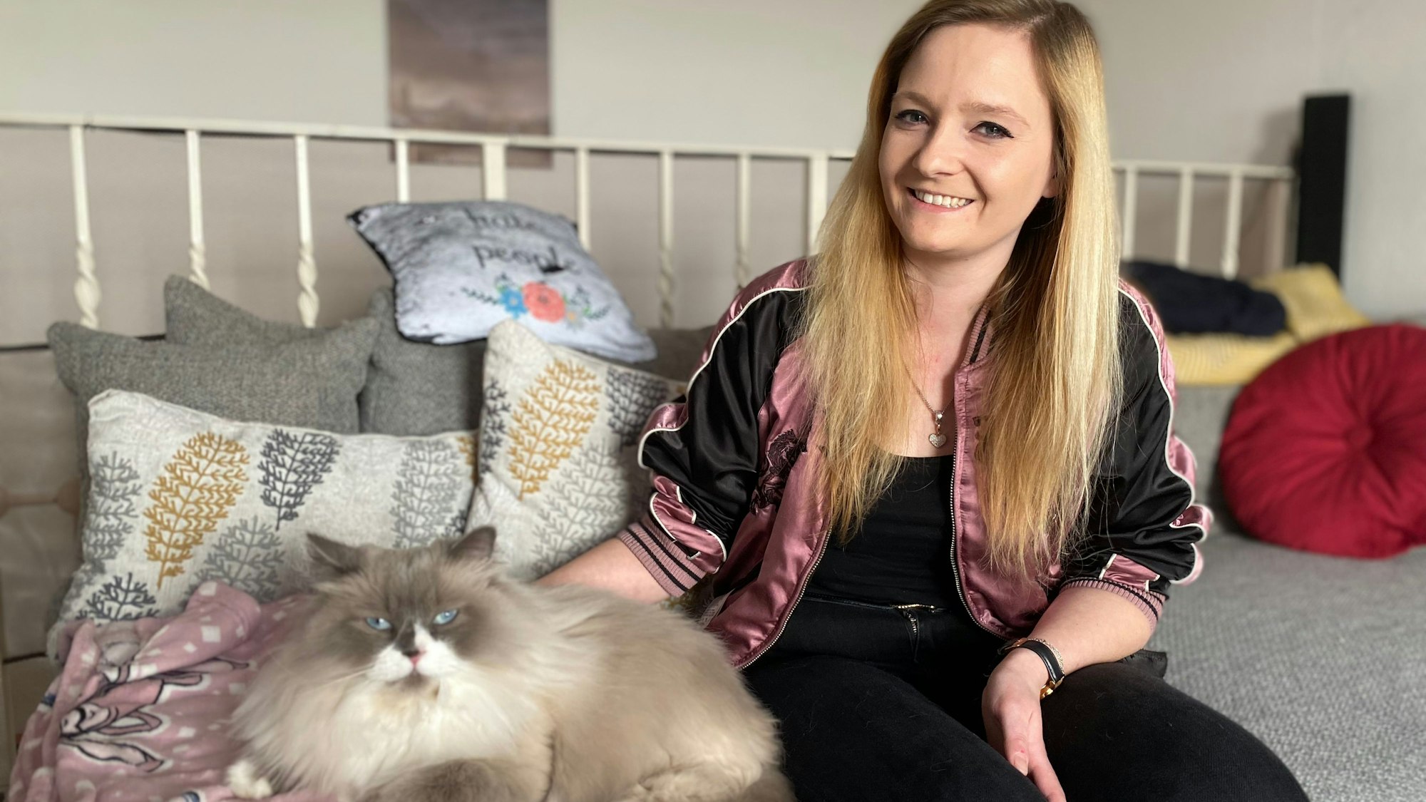 Yasmin Fuhl sitzt gemeinsam mit ihrer Katze auf einer grauen Couch.