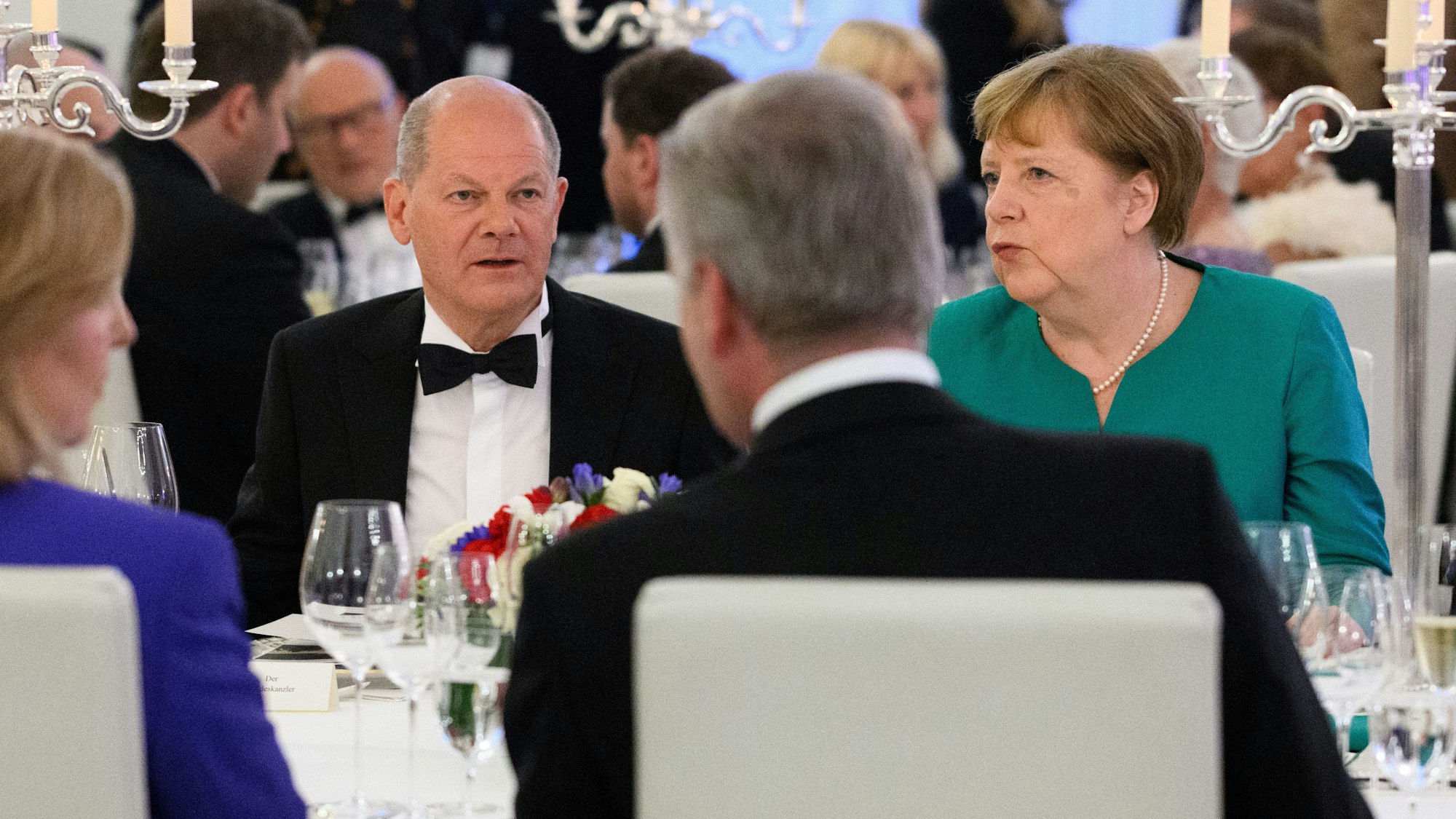 Bundeskanzler Olaf Scholz (SPD) und seine Vorgängerin Angela Merkel (CDU) unterhalten sich beim Staatsbankett zu Ehren des Präsidenten von Frankreich, Macron, und seiner Frau im Schloss Bellevue.