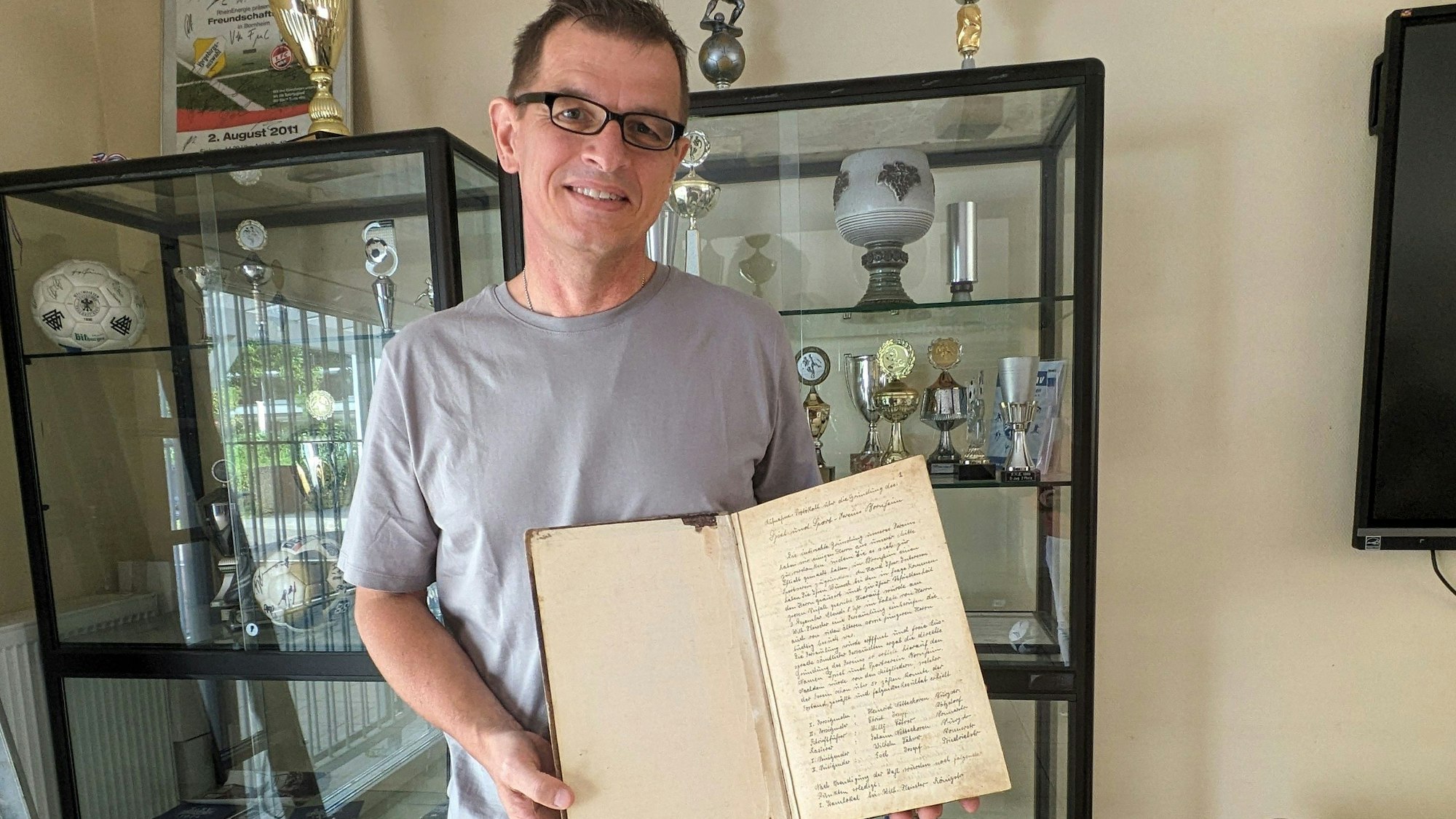 Peter Weiler hat das Gründungsprotokollbuch von 1924 in der Hand.
