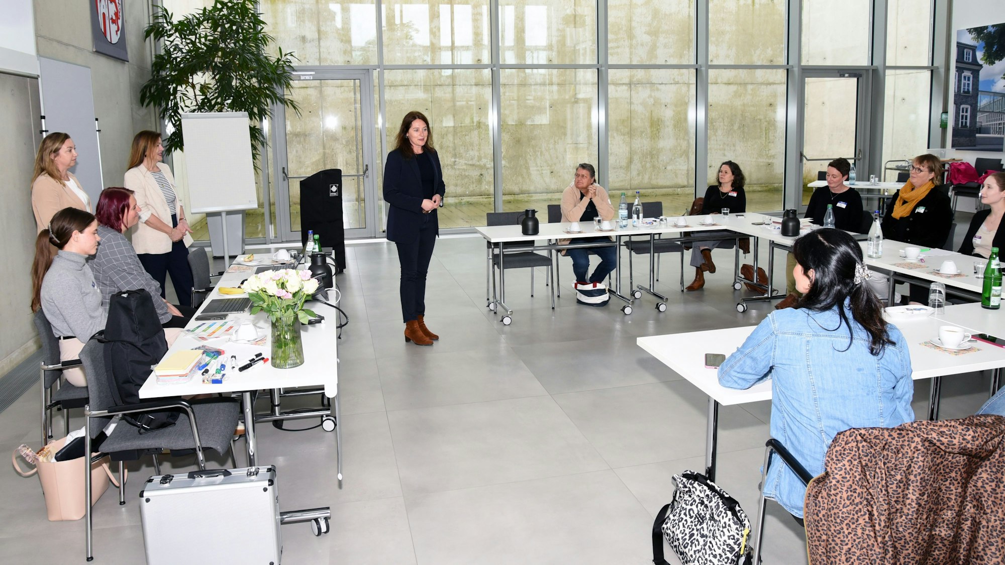 Larissa Weber, Bürgermeisterin in Waldbröl, begrüßt die Teilnehmerinnen eines Workshops, die an einer langen Tischreihe sitzen.