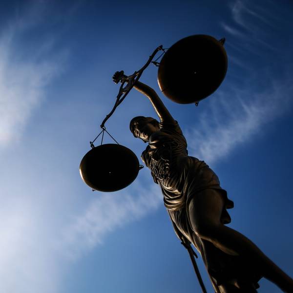 Eine Justitia vor einem Gerichtsgebäude, fotografiert gegen den blauen Himmel.