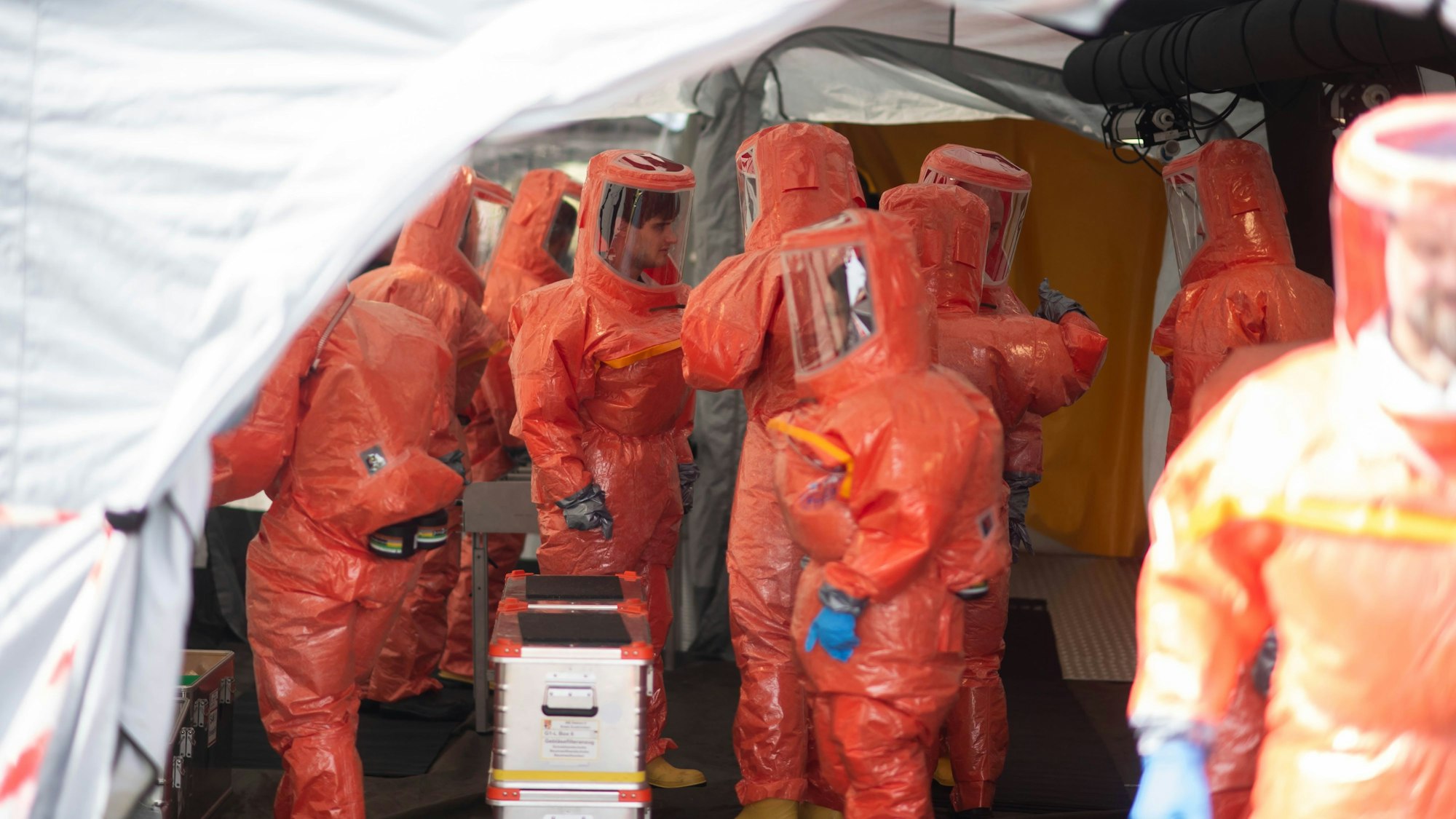 Das Bild zeigt zahlreiche Feuerwehrleute, die Schutzanzüge tragen, um sich vor Kontamination zu schützen.