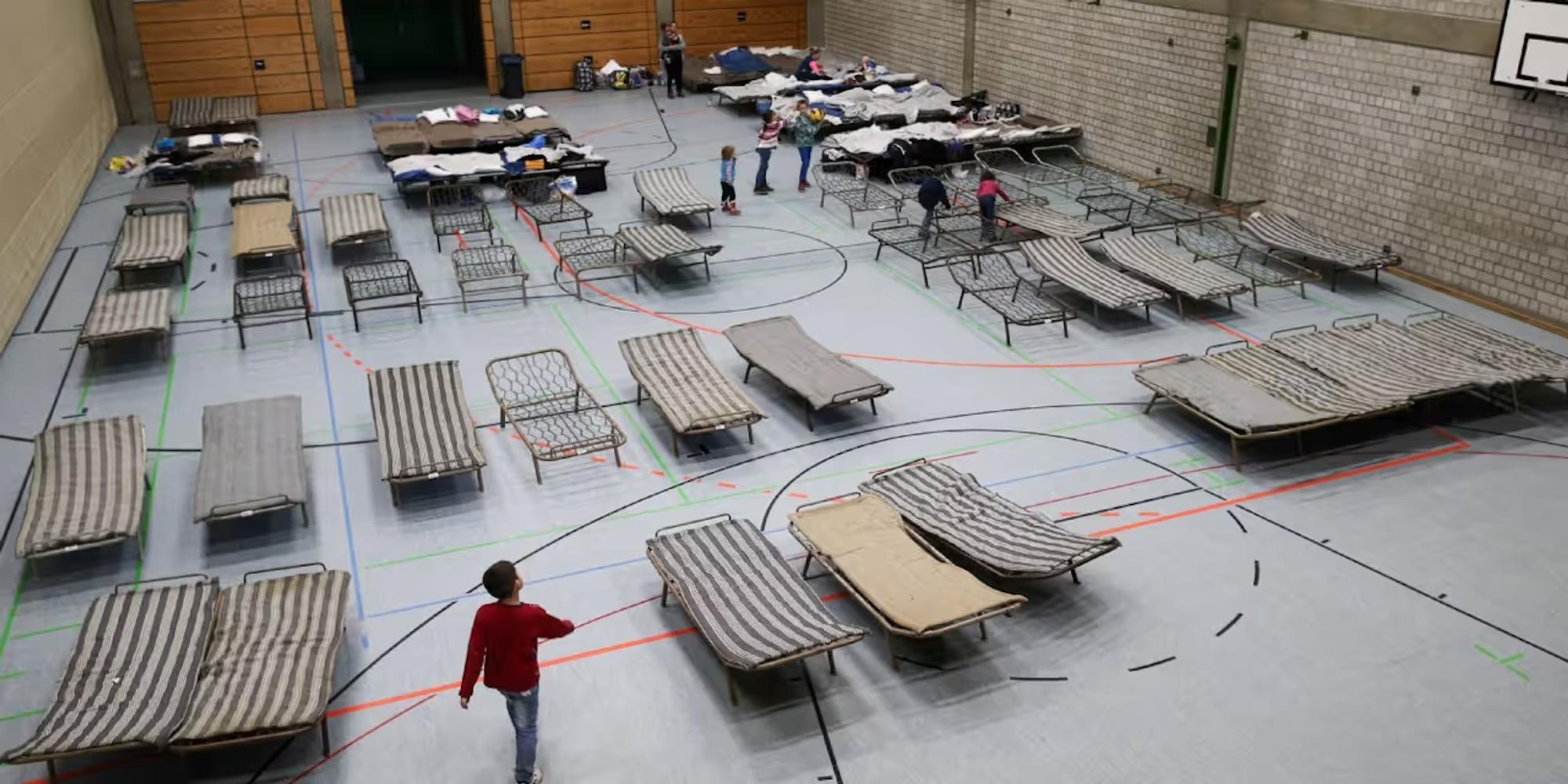 Auf dem Foto ist eine Sporthalle mit Feldbetten zu sehen.