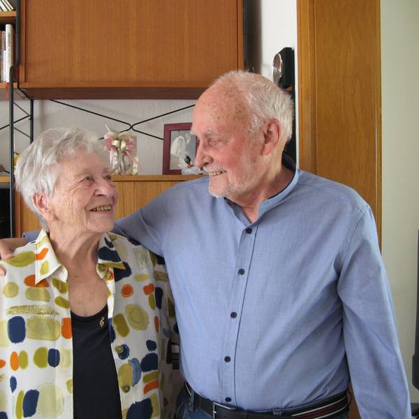 Ein grauhaariger Mann und eine grauhaarige Frau sehen sich tief in die Augen.