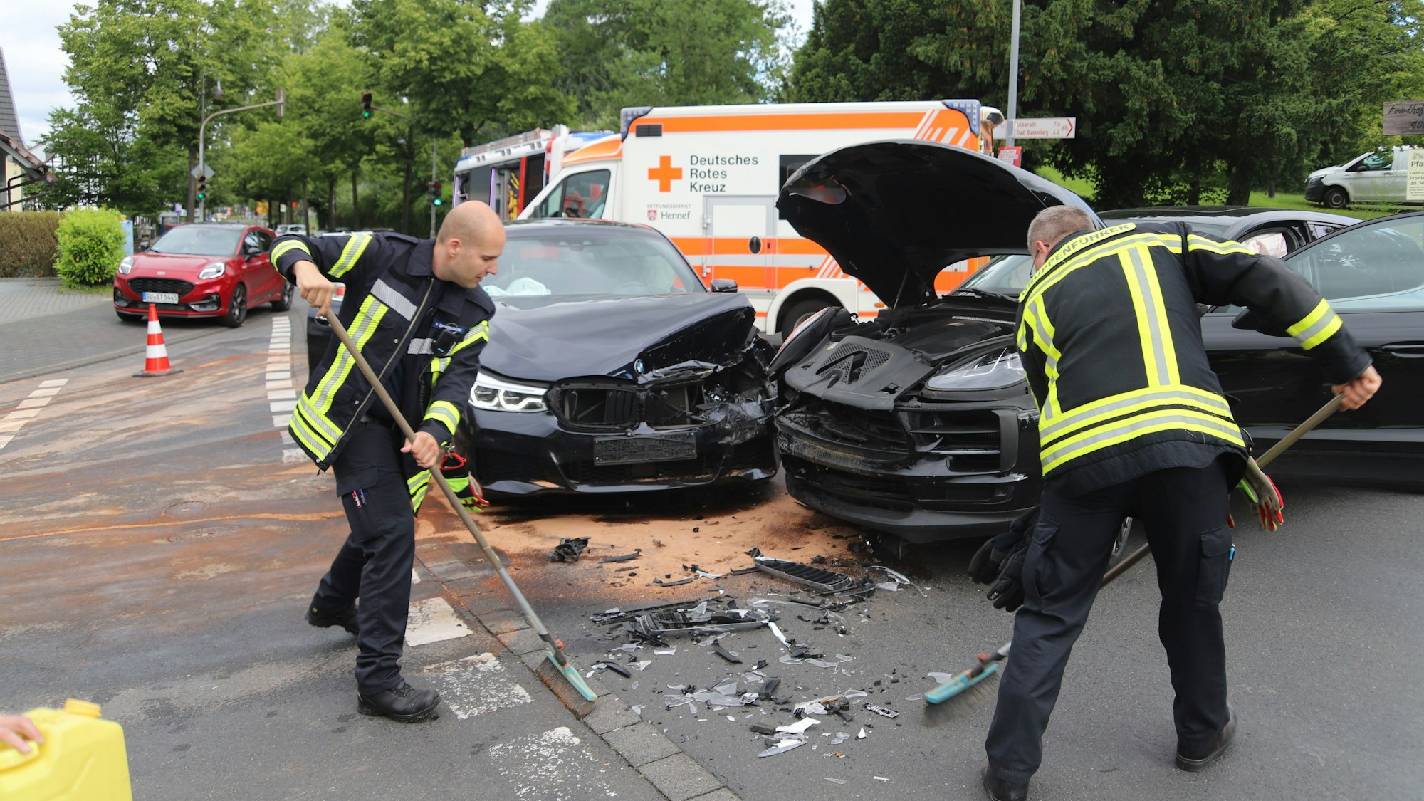 Beim Abbiegen von der Frankfurter in die Hanftalstraße in Hennef hat eine Porschefahrerin die Vorfahrt eines Mercedesfahrers übersehen. Feuerwehrleute reinigen die Fahrbahn.