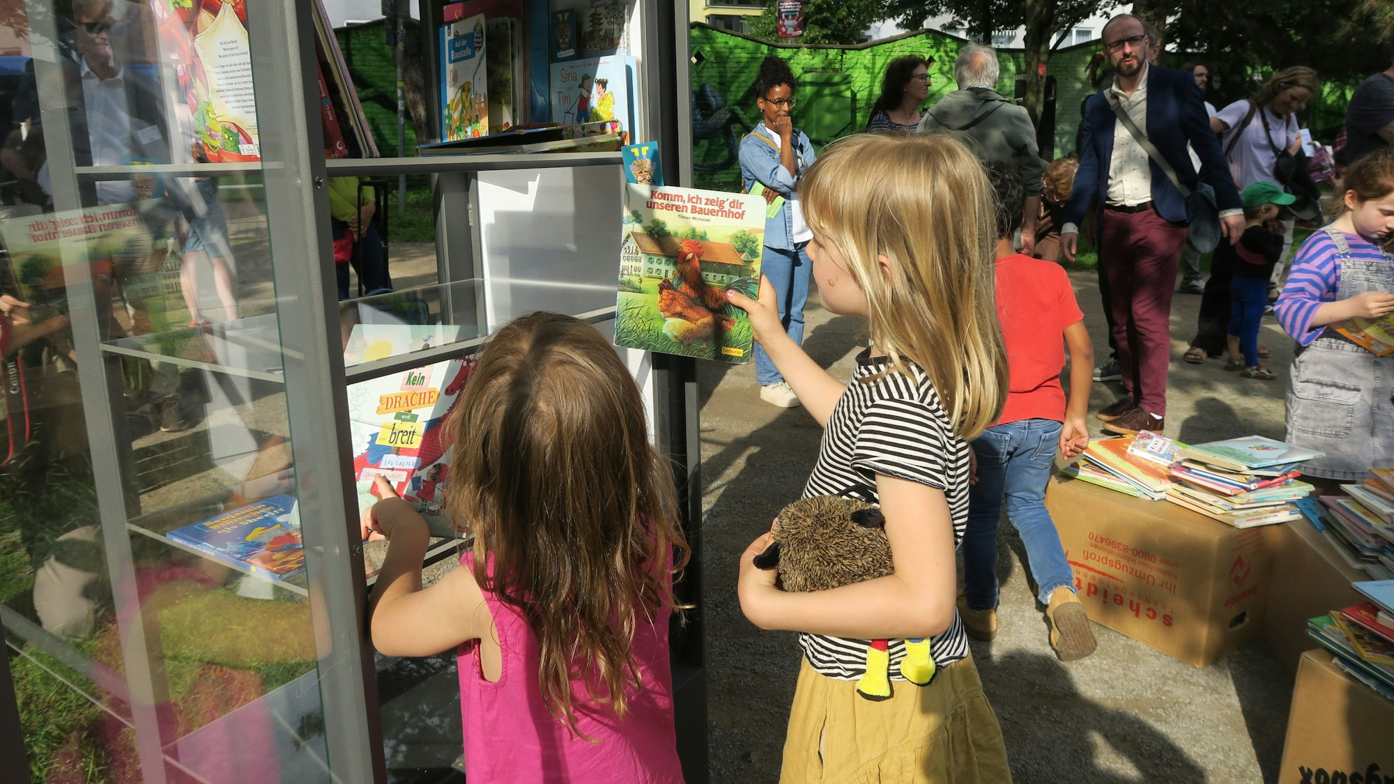 Kinder beim Lesen, Einsortieren der Bücher in den neuen Bücherschrank im Leo-Amann-Park.