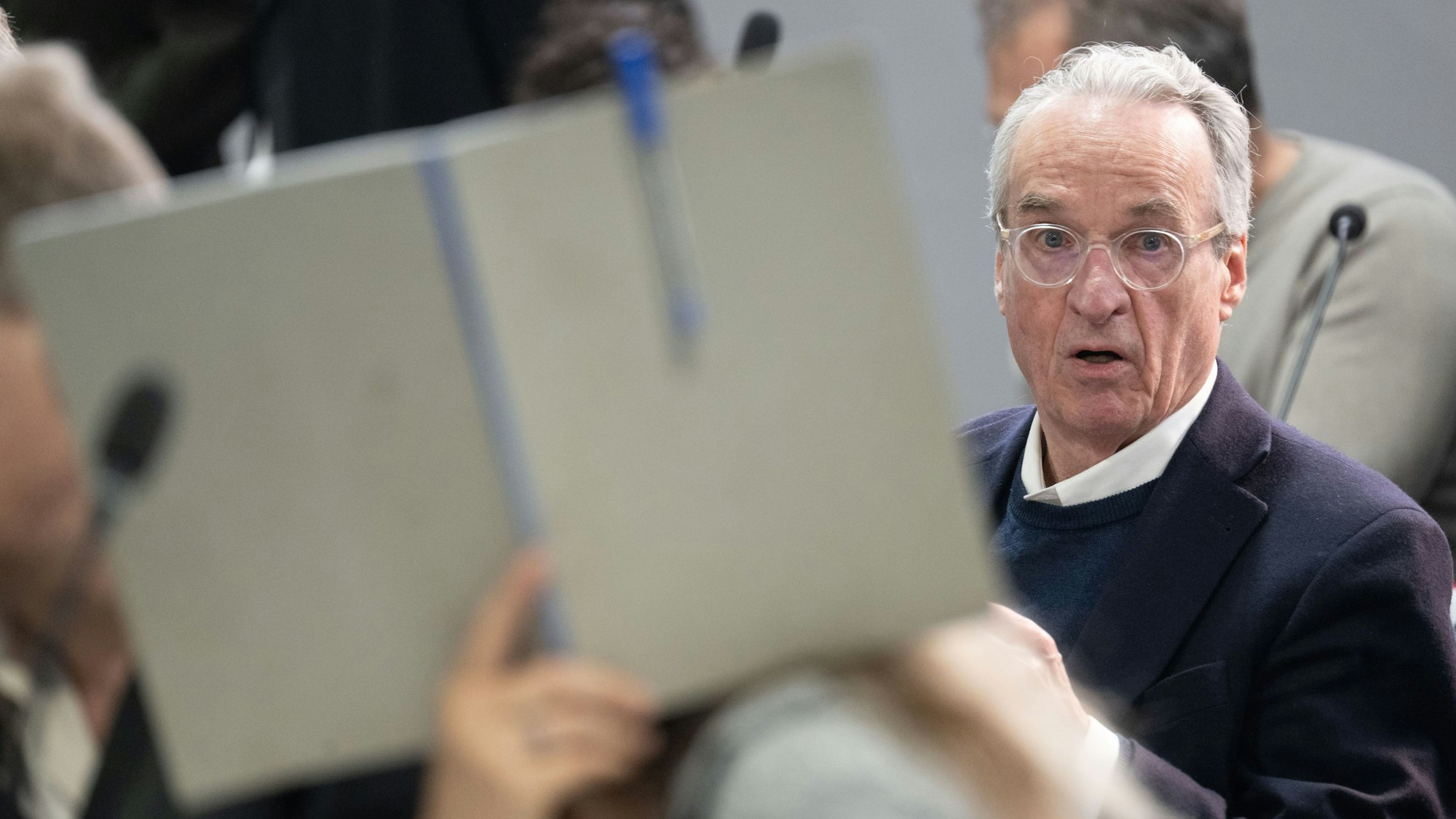 dpatopbilder - 28.05.2024, Hessen, Frankfurt/Main: Der Hauptangeklagte Heinrich XIII. Prinz Reuß sitzt bei der Fortsetzung des Prozesses gegen eine mutmaßliche ·Reichsbürger-Gruppe· um um Prinz Reuß auf der Anklagebank hinter einer Mitangeklagten, die ihr Gesicht mit einer Mappe verdeckt. Die Bundesanwaltschaft legt den insgesamt neun Angeklagten unter anderem die Mitgliedschaft in einer terroristischen Vereinigung zur Last. Foto: Boris Roessler/dpa-POOL/dpa +++ dpa-Bildfunk +++