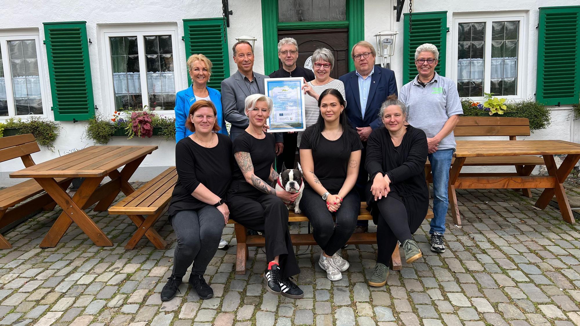 Vor dem neuen Gasthof sitzen und stehen die Familie sowie Vertreter von Leader und aus der Politik.