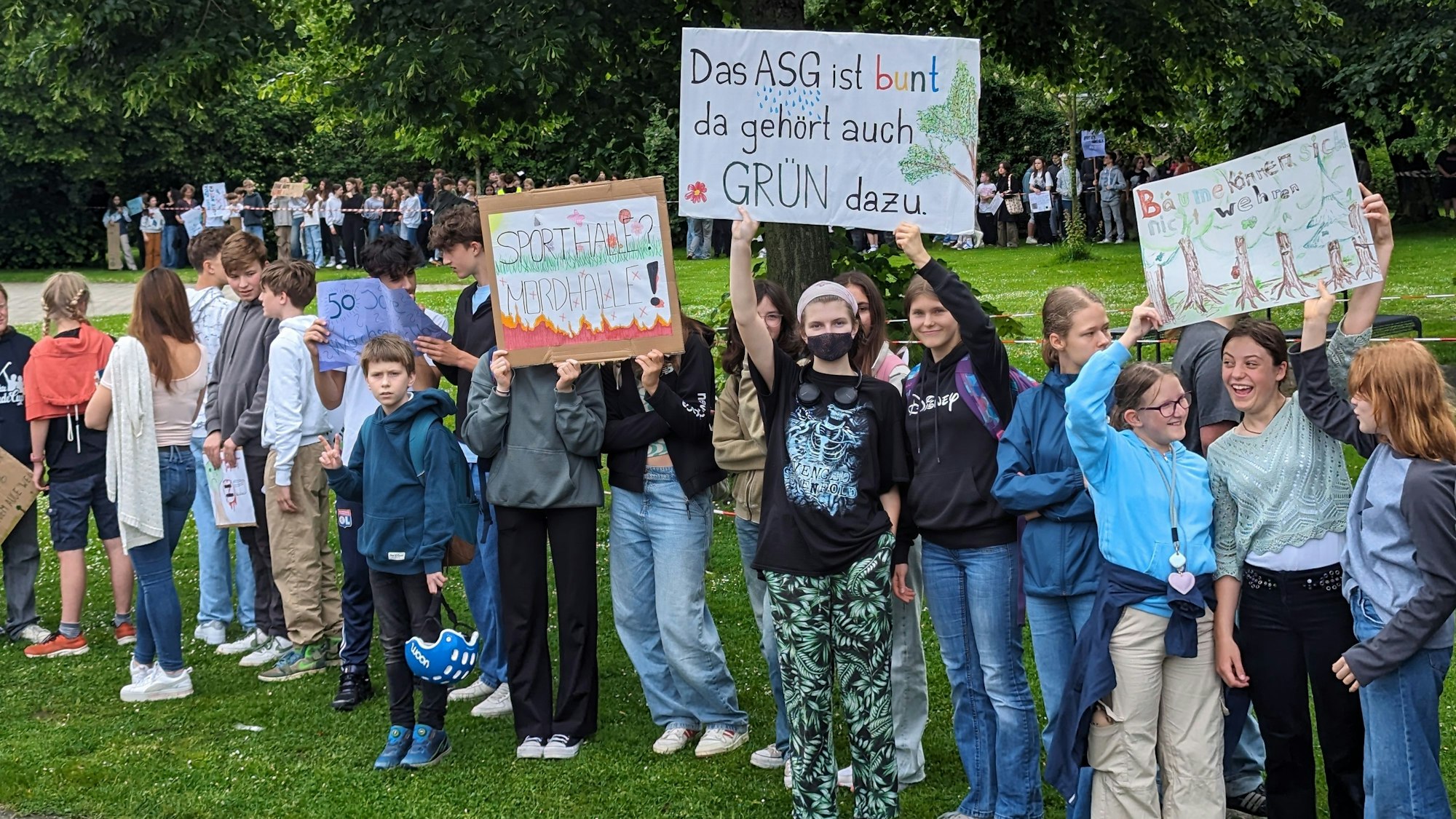 Eine Reihe von Schülerinnen und Schülern mit Protestplakaten vor der Grünanlage auf dem Schulhof des Albert-Schweitzer-Gymnasiums.